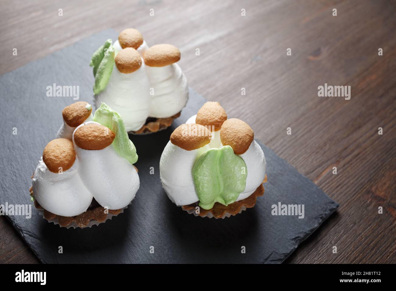 Trois petits gâteaux aux champignons de la crème sur un plateau en pierre.Mise au point sélective. Banque D'Images