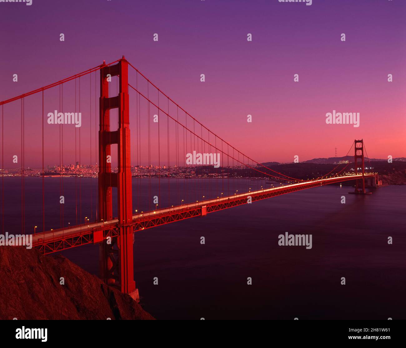 Golden Gate Bridge au coucher du soleil avec lumière chaude et horizon avec des stries de lumière de voiture de Marin Hills, San Francisco, Californie, États-Unis Banque D'Images