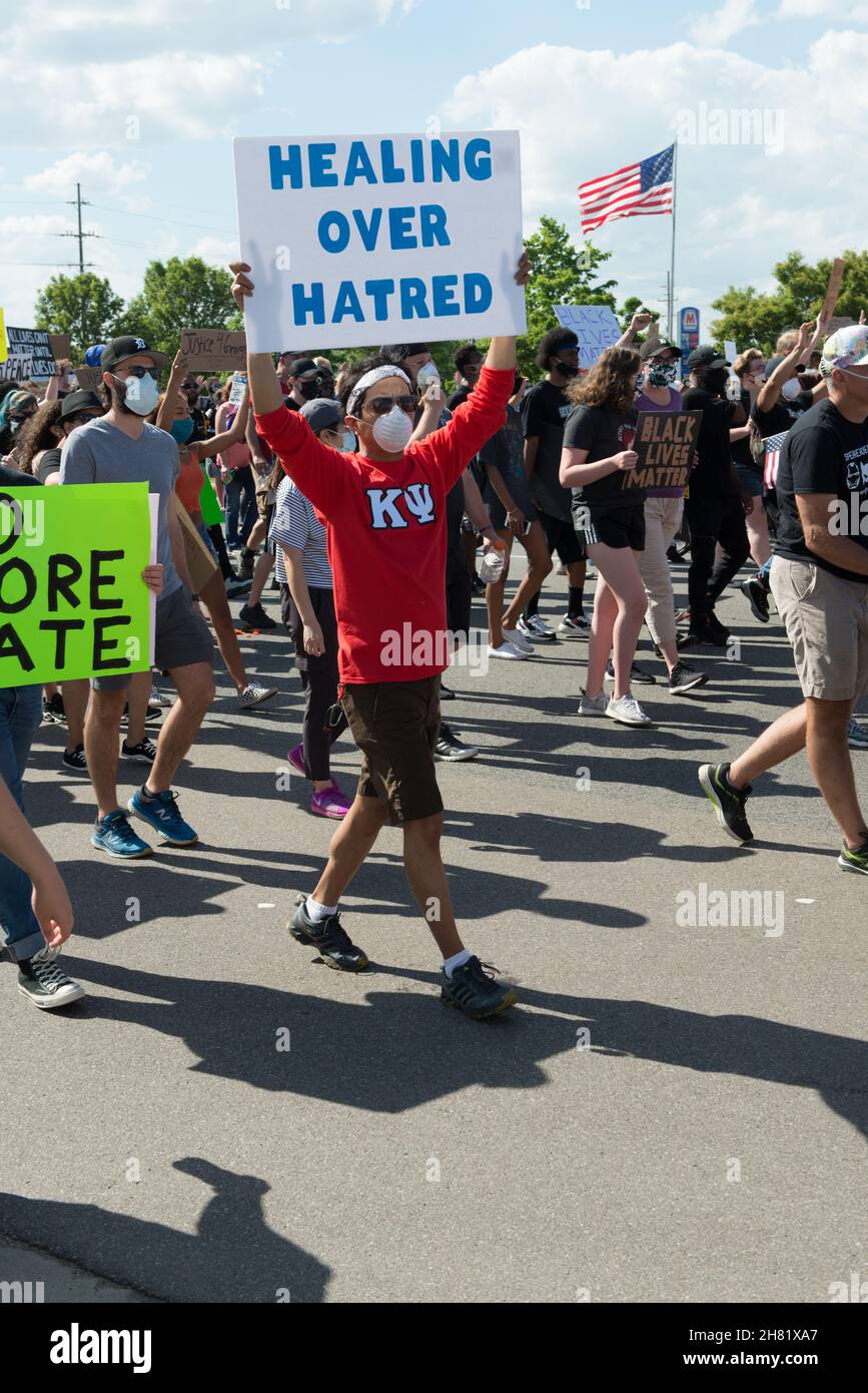 Un jeune homme dans un maillot rouge porte un signe 'Healing over Hate' tout en marchant en soutien de BLM à Sterling Heights, Michigan, le 6 juin 2020. Banque D'Images