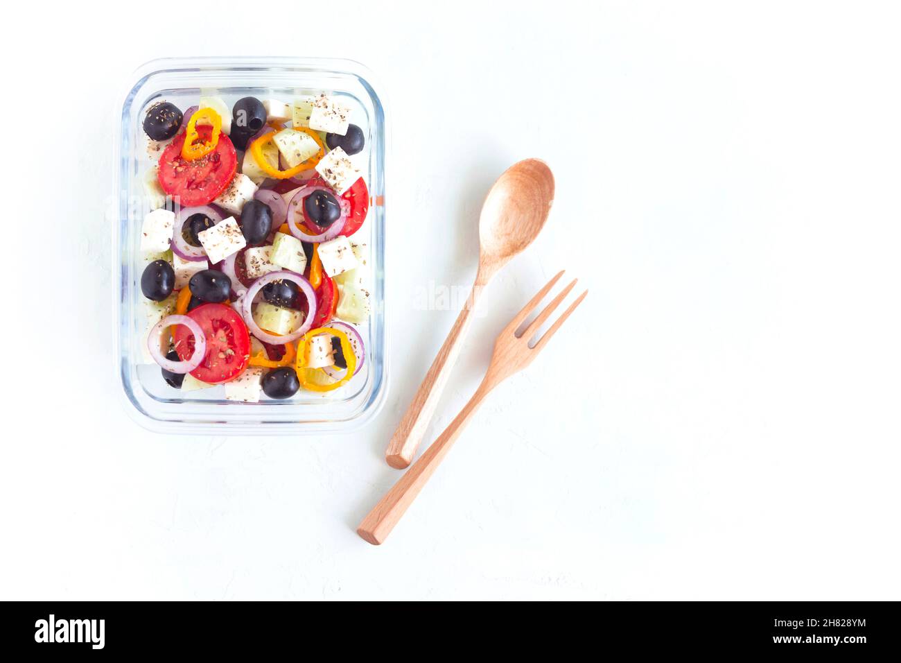 Récipient en verre avec salade grecque sur fond blanc Banque D'Images