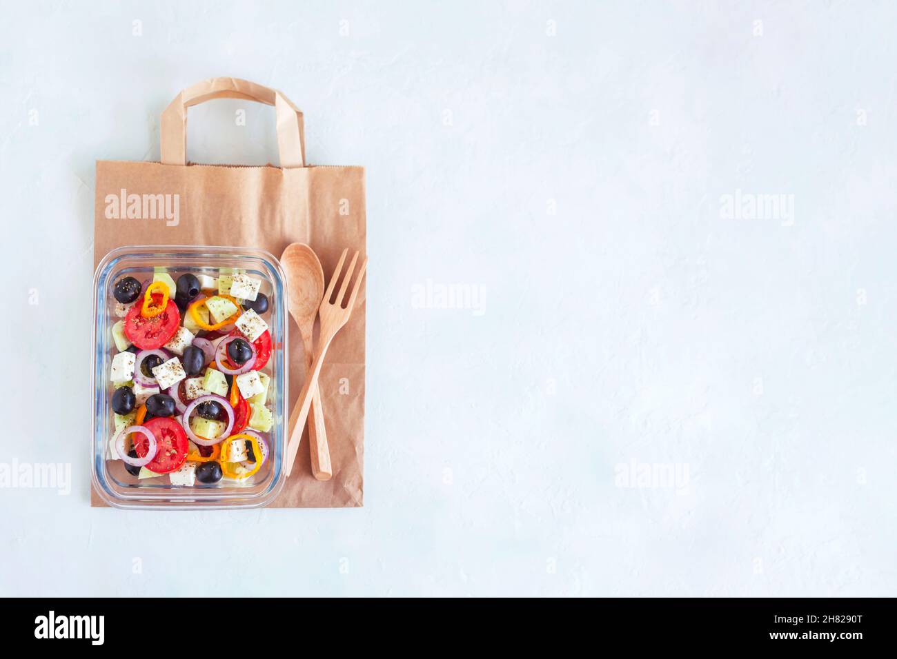 Boîte à lunch avec salade grecque sur le sac en papier, espace de copie Banque D'Images