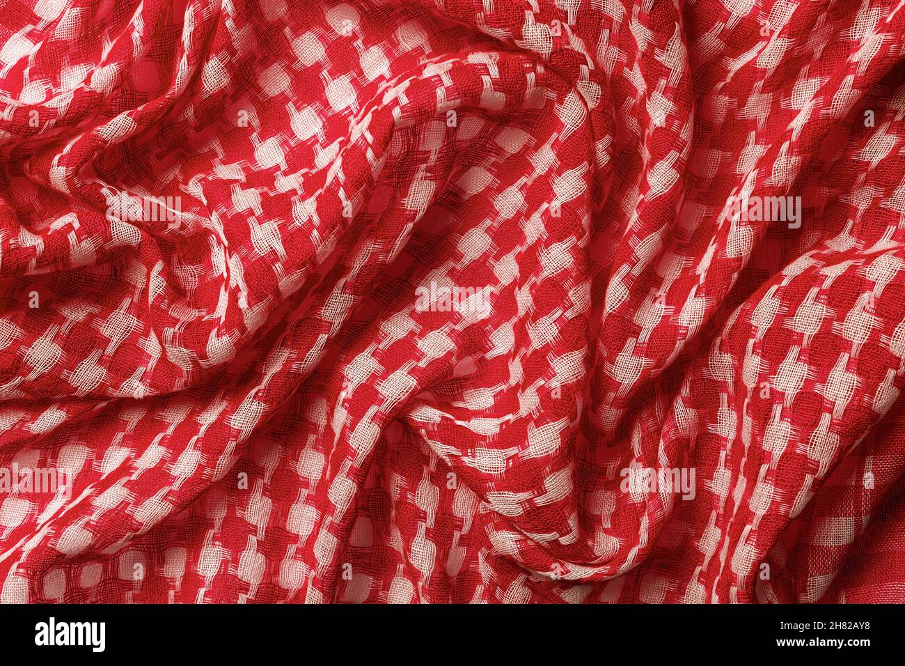 Un shémagh drapé de couleurs rouges et blanches sur le fond.Foulard du désert arabe texture hirbawi.Coton plié keffiyeh macro.Motif kefia plein format.Traditionnel Banque D'Images