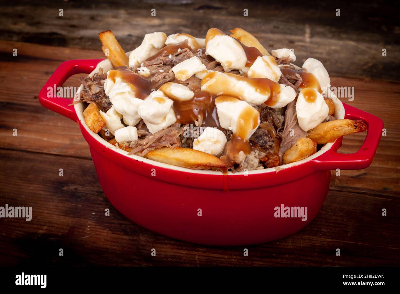 la coutine de confit de canard sur une table en bois est un repas canadien préparé avec de la sauce aux frites et des carets de fromage Banque D'Images