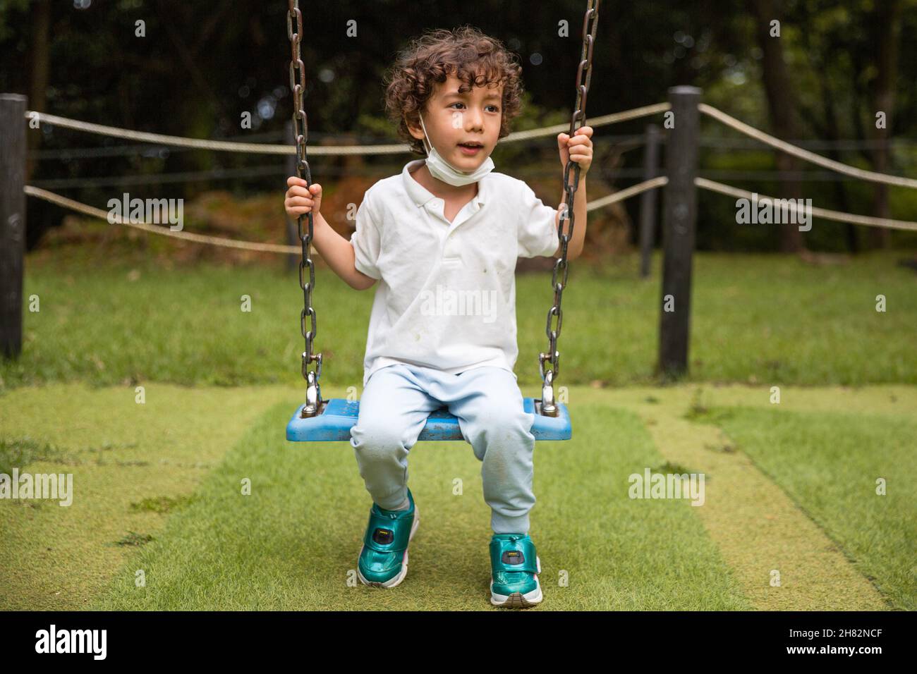 L'enfant sur une balançoire à l'aire de jeux Banque D'Images