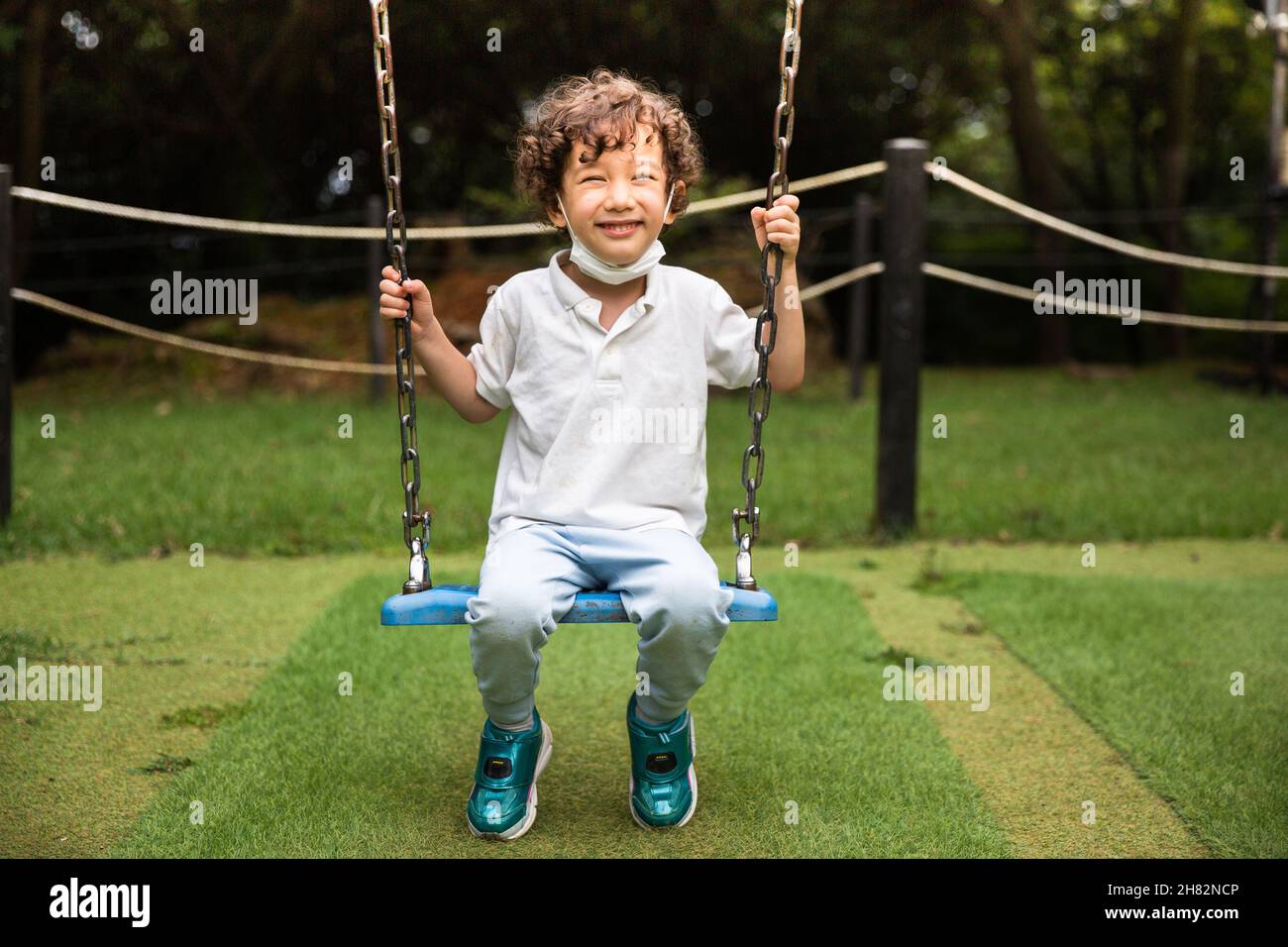 Enfant sur une balançoire dans l'aire de jeux Banque D'Images