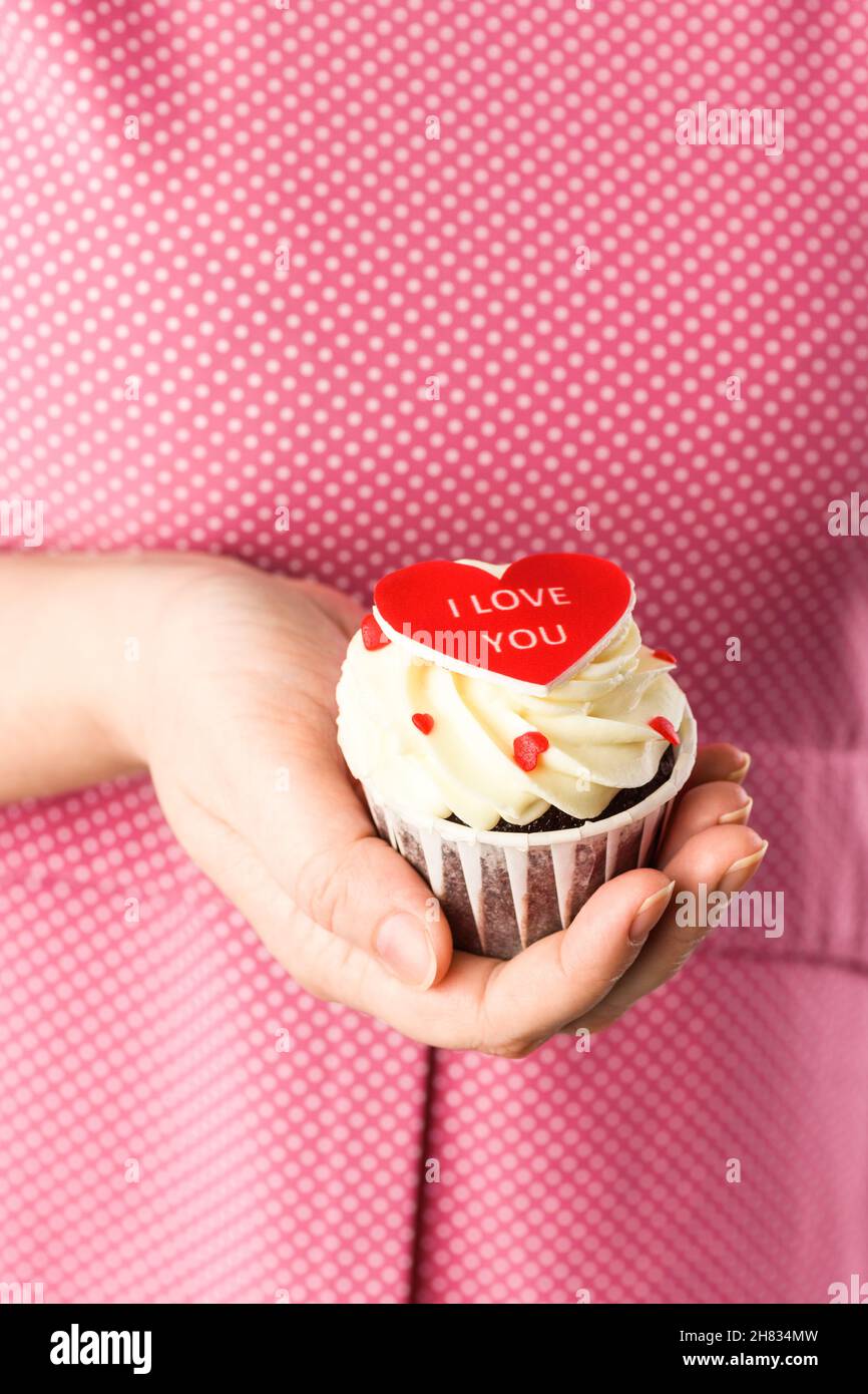 Gâteau en forme de coeur dans les mains avec l'inscription I Love You sur fond rose.Cupcake en gros plan en forme de coeur Banque D'Images