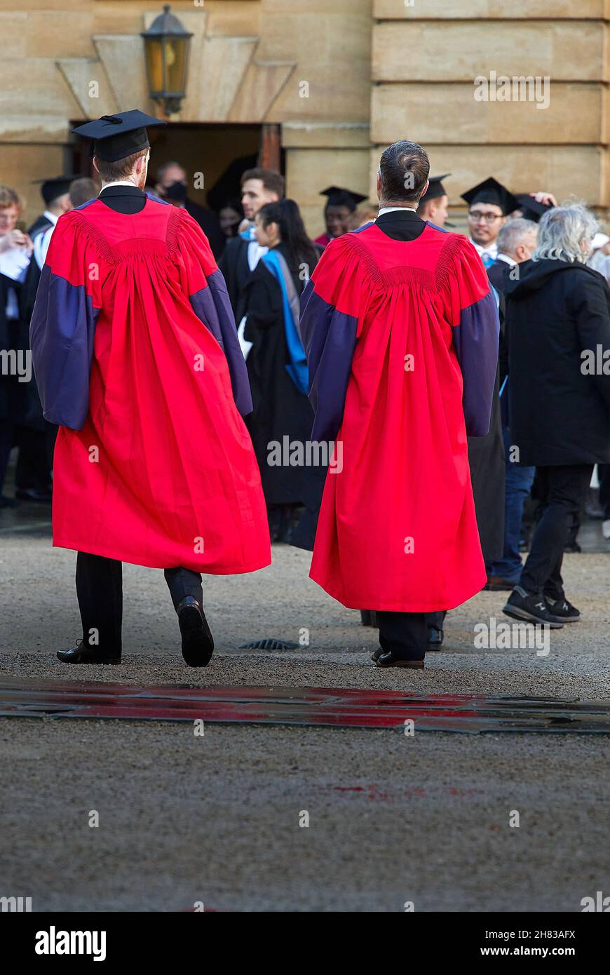 Des étudiants de troisième cycle réussis dans le quadrilatère Clarendon de la bibliothèque Bodleian après leur cérémonie de remise de leur diplôme au théâtre Sheldonian de l'université d'Oxford, le 26 novembre 2021, sur un plan humide. Banque D'Images