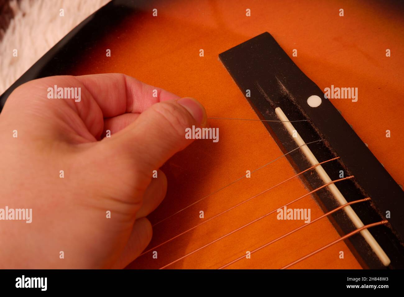 Réparer une guitare cassée en reconnectant la corde métallique Photo Stock  - Alamy