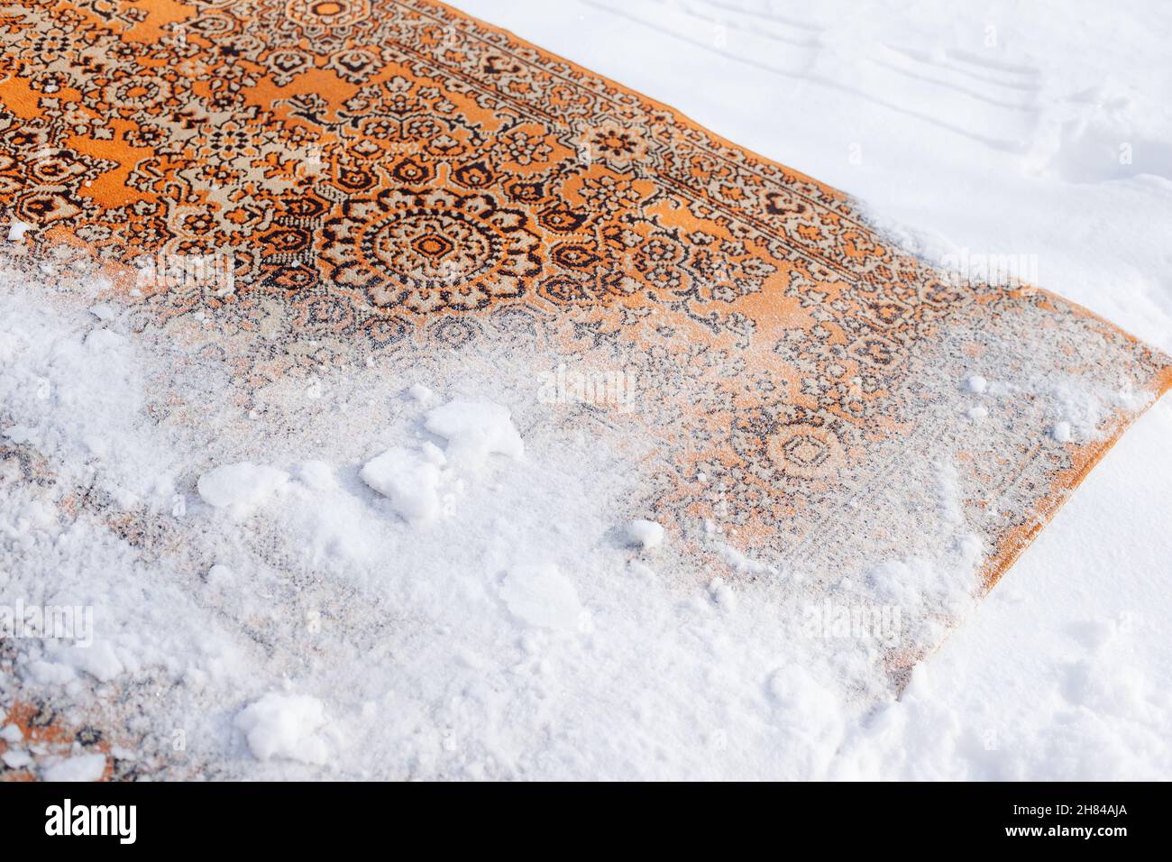 Gros plan de la moquette dans la neige.Le vieux tapis persan dans les tons  rouges est retourné et arrosé de neige sur le dessus pour le nettoyer Photo  Stock - Alamy