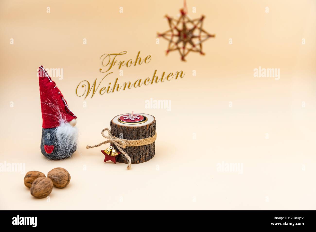 Carte postale de Noël avec texte Frohe Weihnachten et fond beige, noix, bougie en bois et gnome drôle Banque D'Images