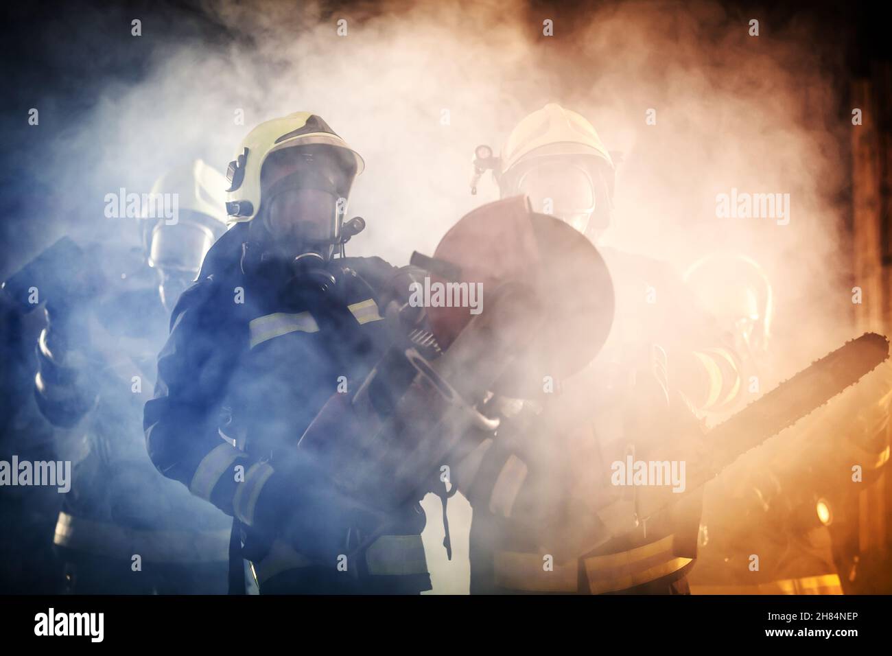 Groupe de pompiers professionnels portant tout l'équipement, des masques à oxygène et des outils de secours d'urgence, une scie circulaire hydraulique et à gaz, une hache et un traîneau Banque D'Images