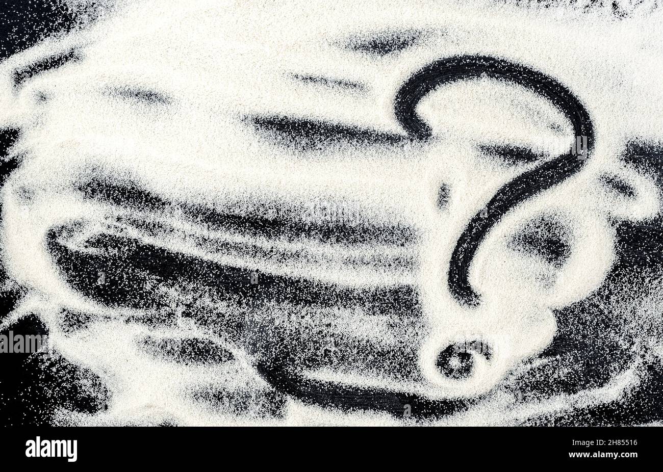 Fond de farine noire.Gros plan du point d'interrogation sur le mélange de farine Banque D'Images