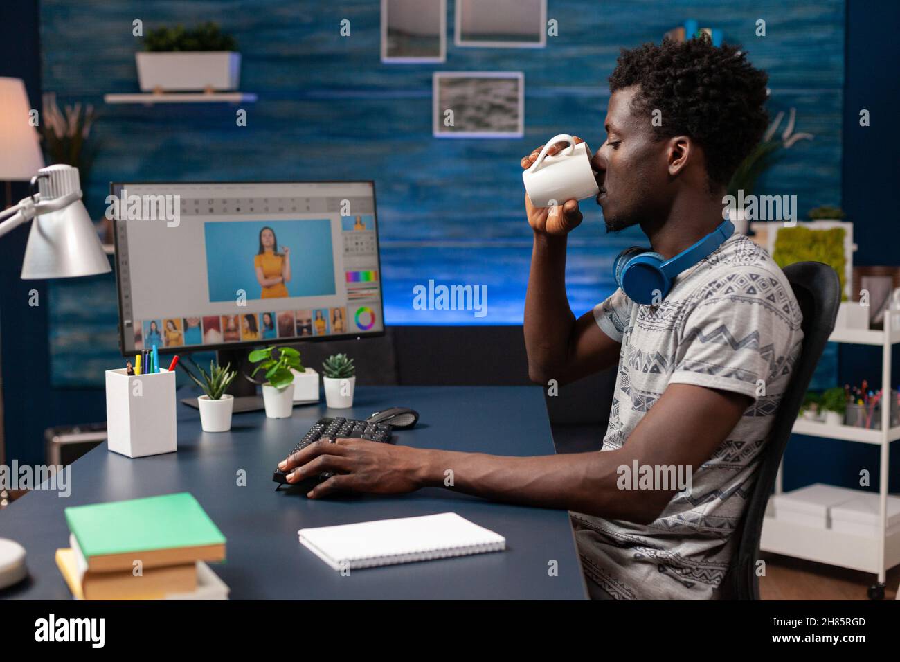Photographe afro-américain buvant du café tout en éditant des photographies numériques à l'aide d'un logiciel de montage de post-production.Jeune éditeur d'illustrateur travaillant à distance à la retouche de photos dans le studio de créativité Banque D'Images