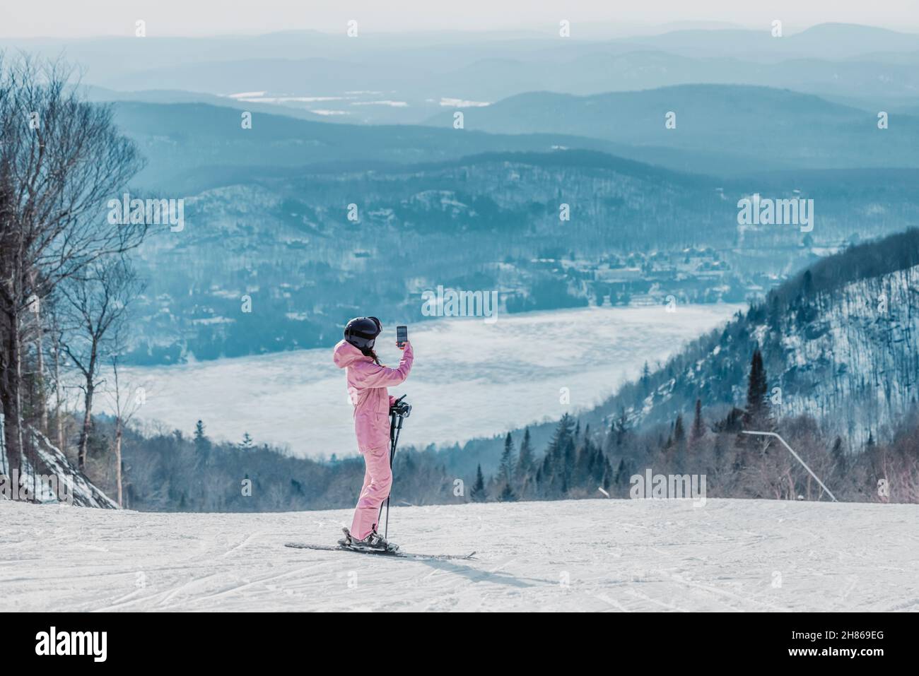 Femme prenant des photos de vacances de ski avec le téléphone - femme skieuse utilisant l'application de téléphone sur la piste de ski prenant des photos de paysage naturel d'hiver étonnant Banque D'Images