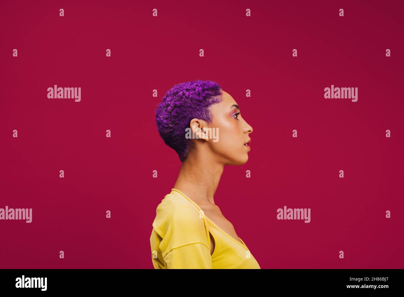 Cheveux violets à bascule.SideView d'une jeune femme à la mode portant des cheveux violets dans un studio.Jeune femme élégante qui a l'air confiante en se tenant de nouveau debout Banque D'Images