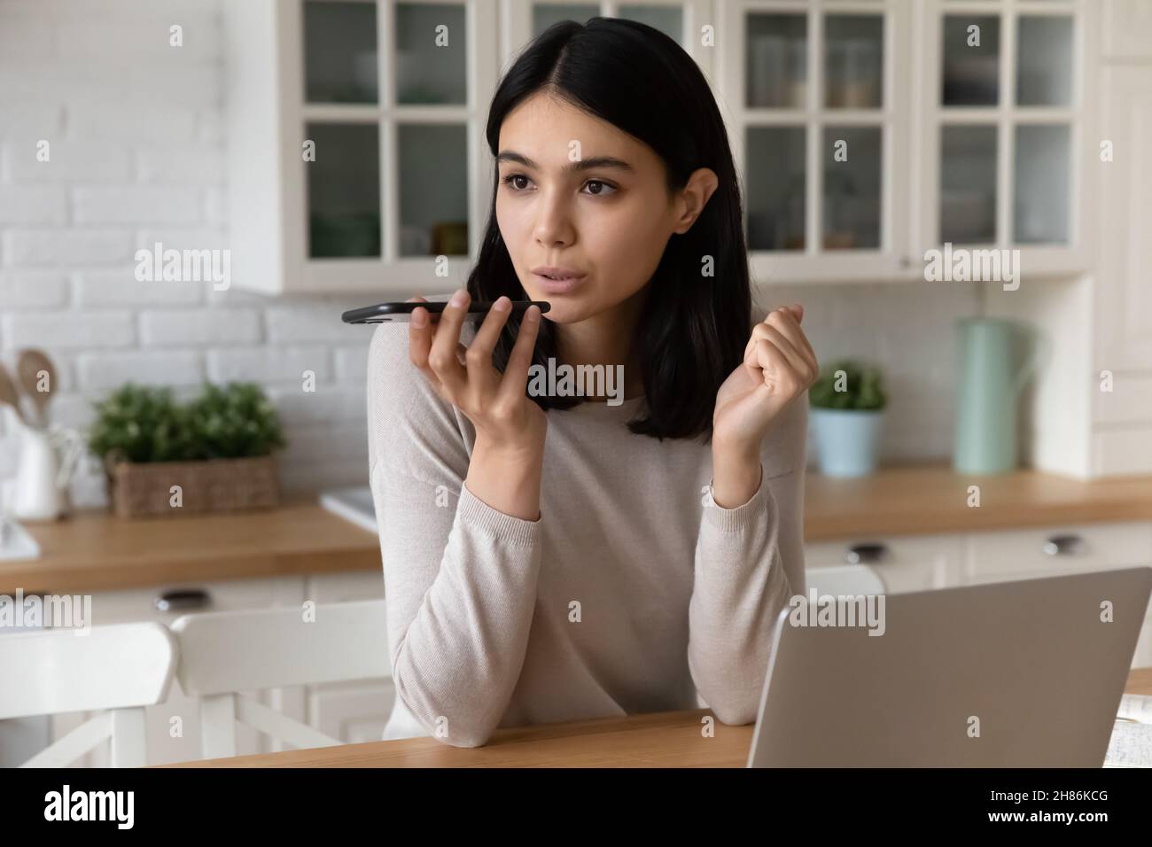 Une jeune femme asiatique qui parle avec son haut-parleur peut résoudre ses problèmes de travail à domicile Banque D'Images