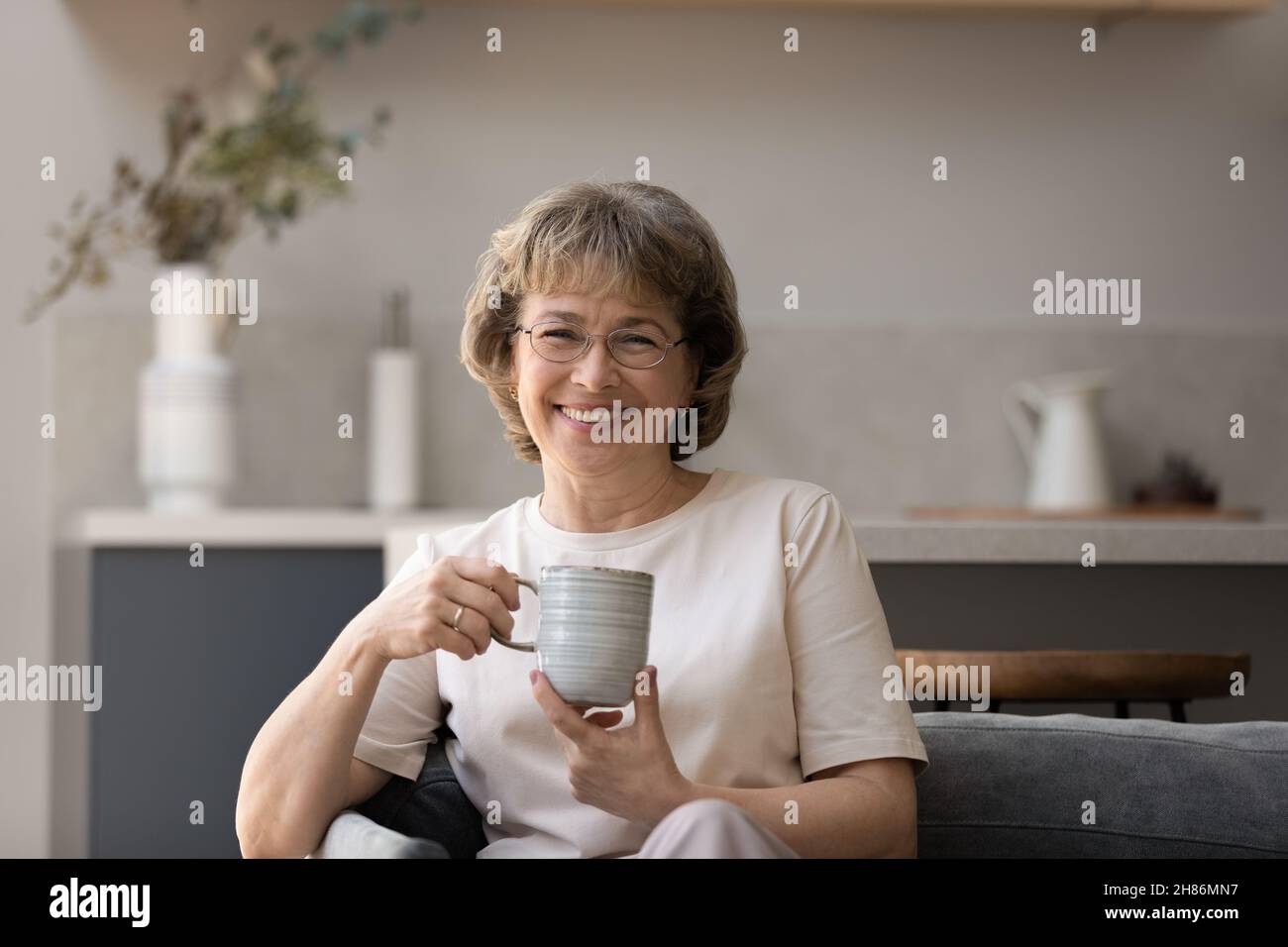 Bonne femme âgée dans les verres appréciant le matin Banque D'Images