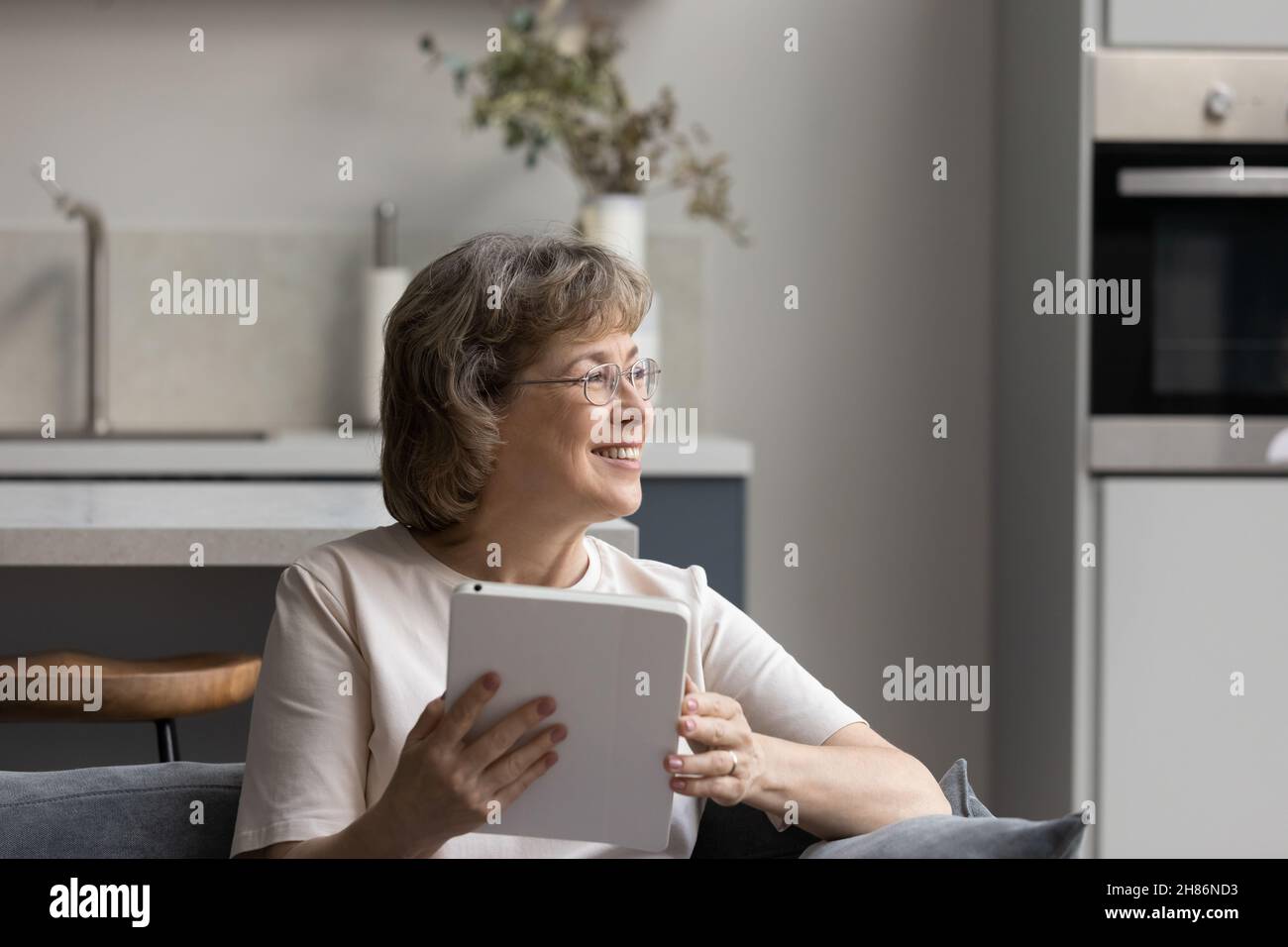 Bonne femme mûre et attentionnés assise sur le canapé en bonne pensée Banque D'Images