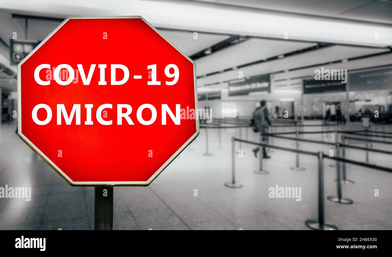 Covid-19 Omicron écrit sur le panneau d'arrêt avec les passagers arrivant au contrôle de passeport dans l'aéroport générique Banque D'Images