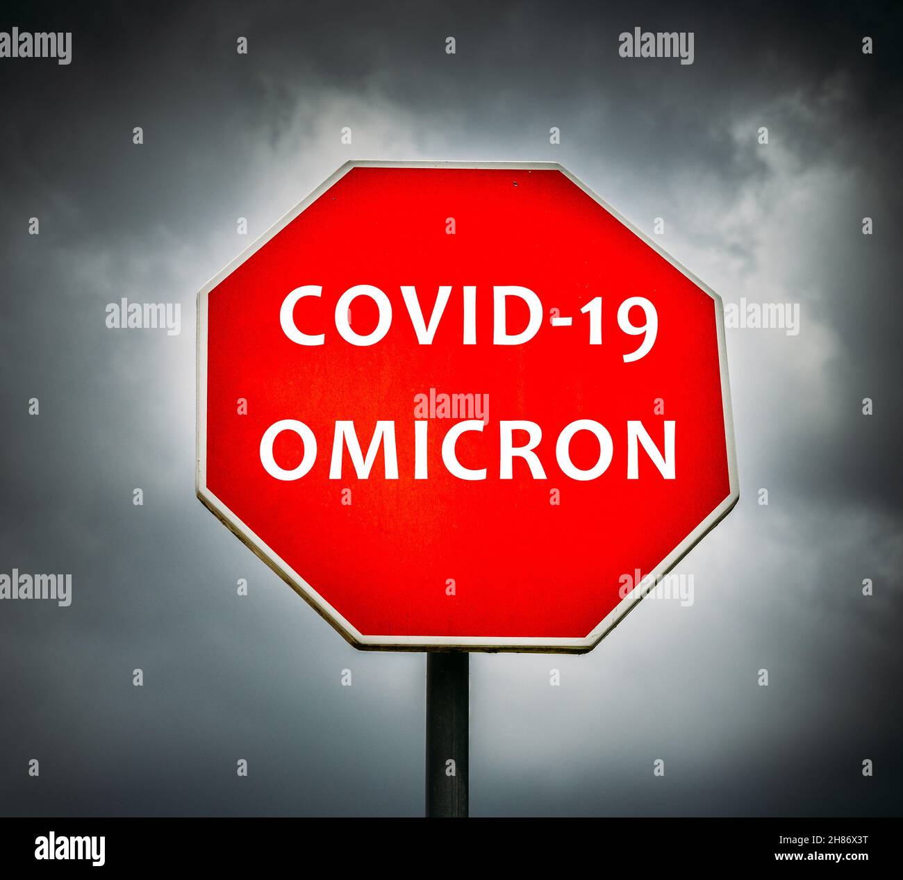 Covid-19 Omicron écrit sur le panneau stop avec des nuages orageux en arrière-plan Banque D'Images