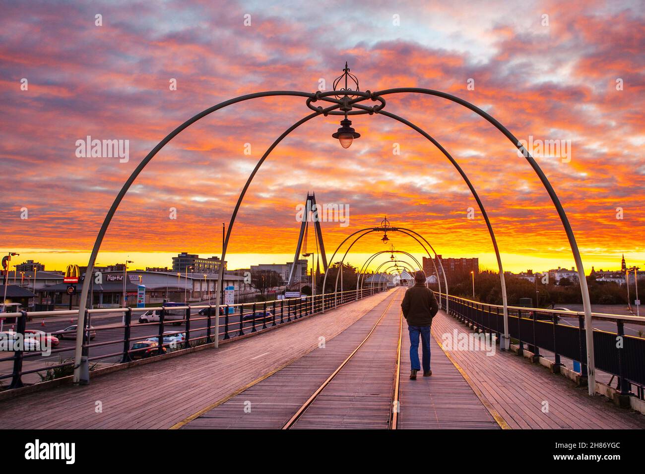 Southport, Merseyside.Météo Royaume-Uni.28 novembre 2021.Ciel rouge le matin -2C à l'aube tandis que les marcheurs de la jetée se promènent tôt le matin sur la jetée en fer victorienne du complexe.Aujourd'hui, les nuages vont s'y déplacer du nord et une petite pluie, de la neige et du luette se développeront.Une journée froide avec une douce brise du nord-ouest.Crédit; MediaWorldImages/AlamyLiveNews Banque D'Images