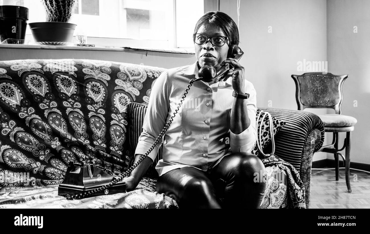 Une femme afro-américaine parle au téléphone en noir et blanc Banque D'Images