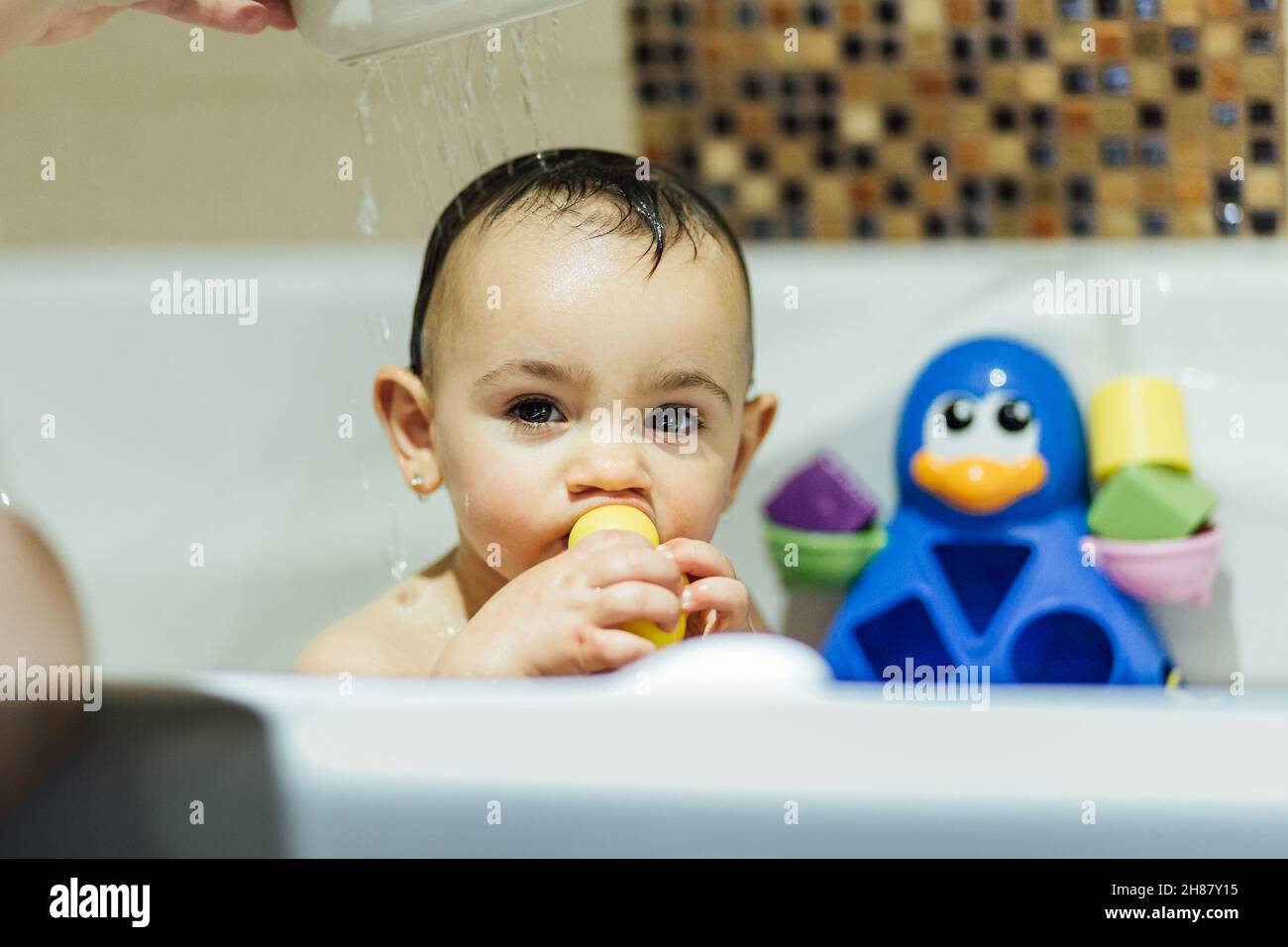 Petite fille jouant avec des jouets en caoutchouc tout en appréciant le temps de bain. Banque D'Images