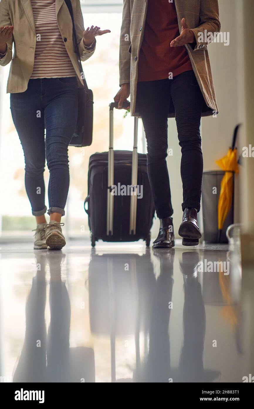 Deux jeunes gens d'affaires traversent le couloir de l'hôtel dans une atmosphère détendue lors d'un voyage d'affaires.Affaires, personnes, hôtel, voyage Banque D'Images