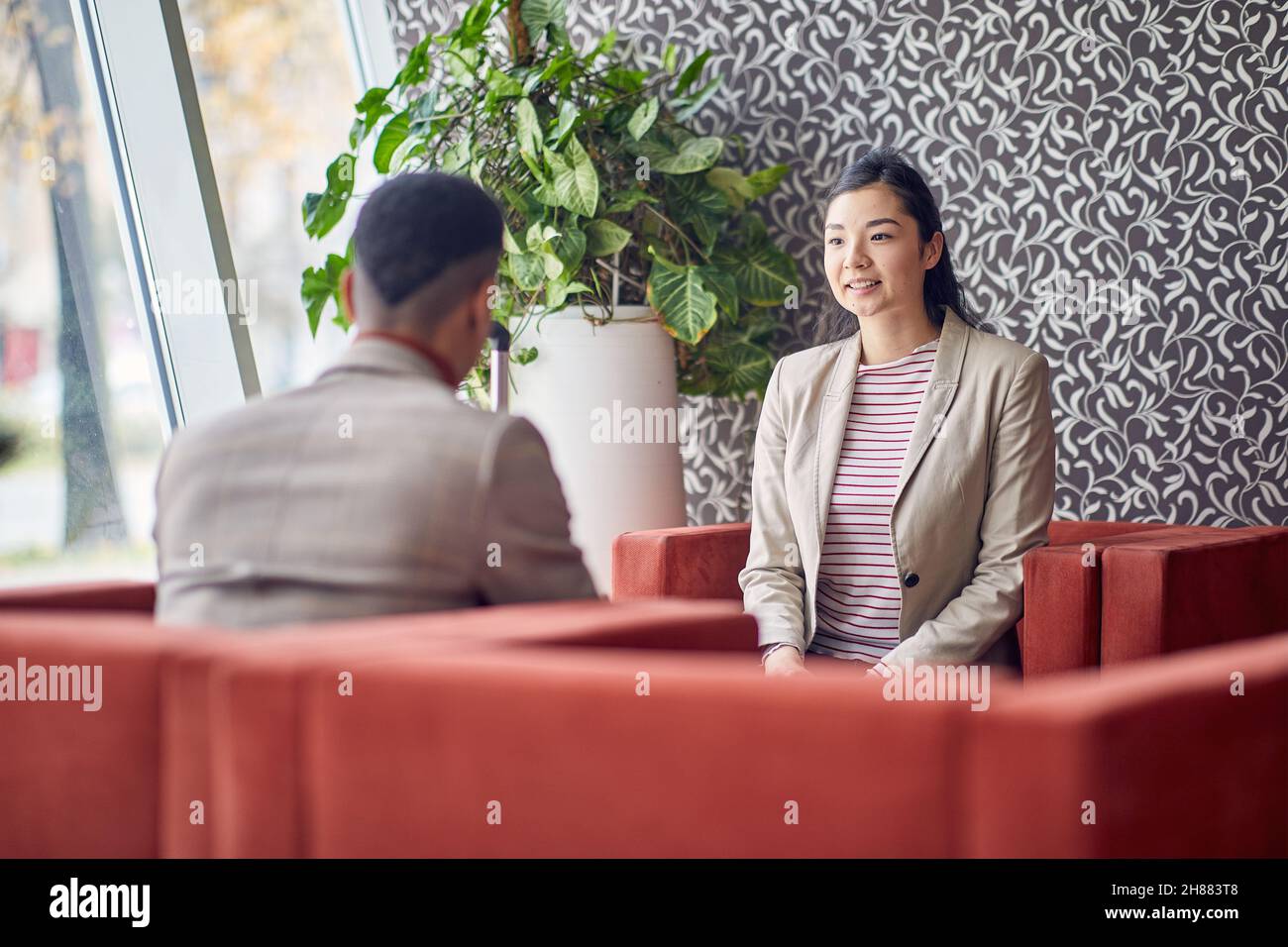 Deux jeunes gens d'affaires sont assis et bavardent dans une atmosphère détendue dans le hall de l'hôtel pendant un voyage d'affaires.Affaires, personnes, hôtel, voyage Banque D'Images