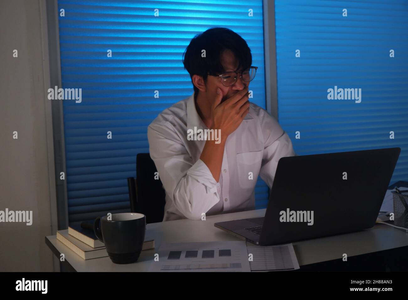 Un jeune homme d'affaires asiatique travaille tard dans la nuit. Banque D'Images
