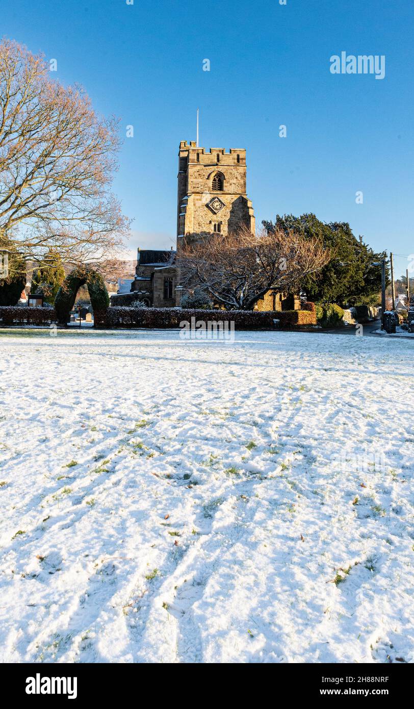Une église de village construite en pierre contre un ciel vert et bleu de village couvert de neige Banque D'Images