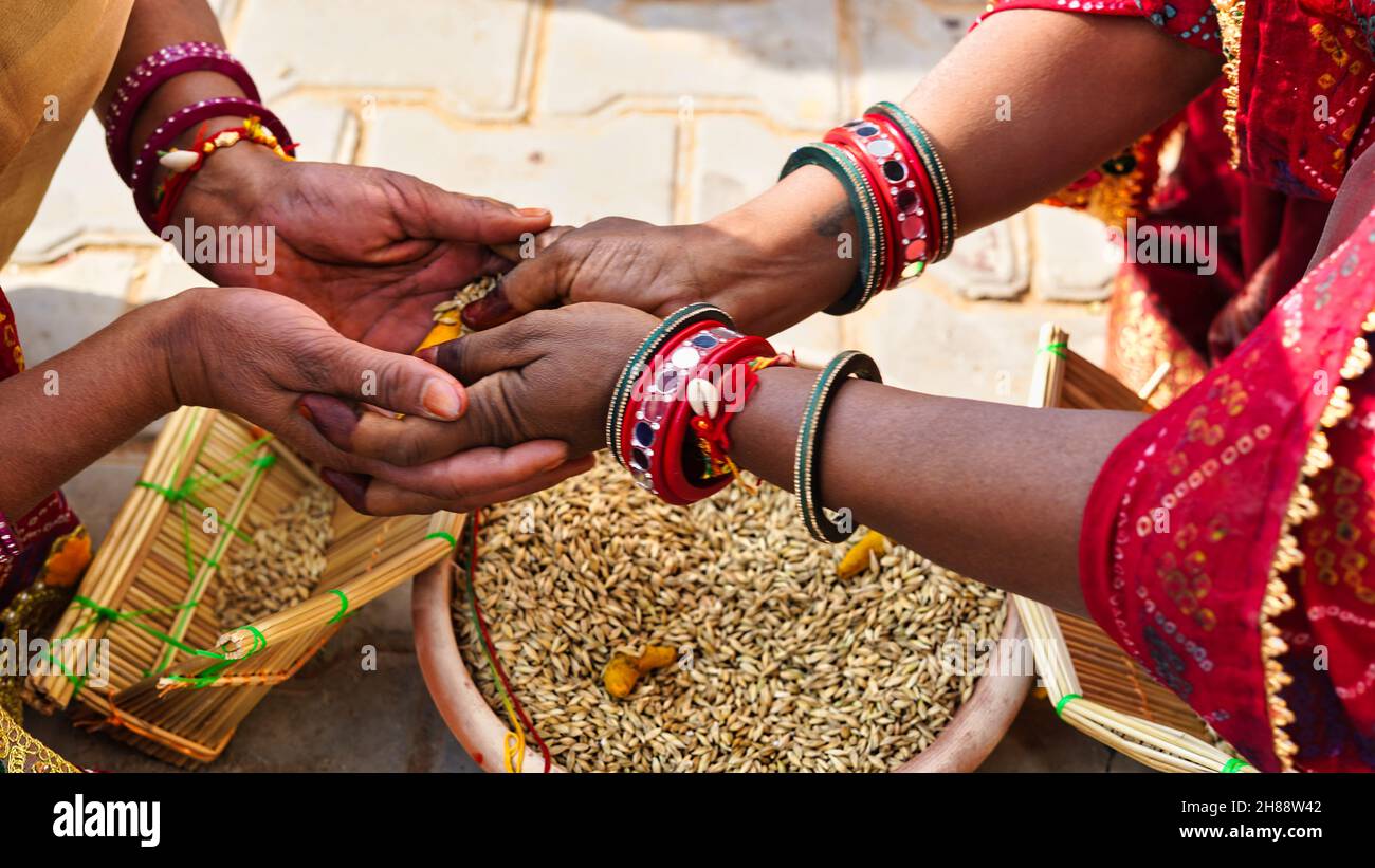 Deux femmes indiennes célèbrent des rituels de mariage avec des choses saintes comme la graine de sorgho et le curcuma. Banque D'Images