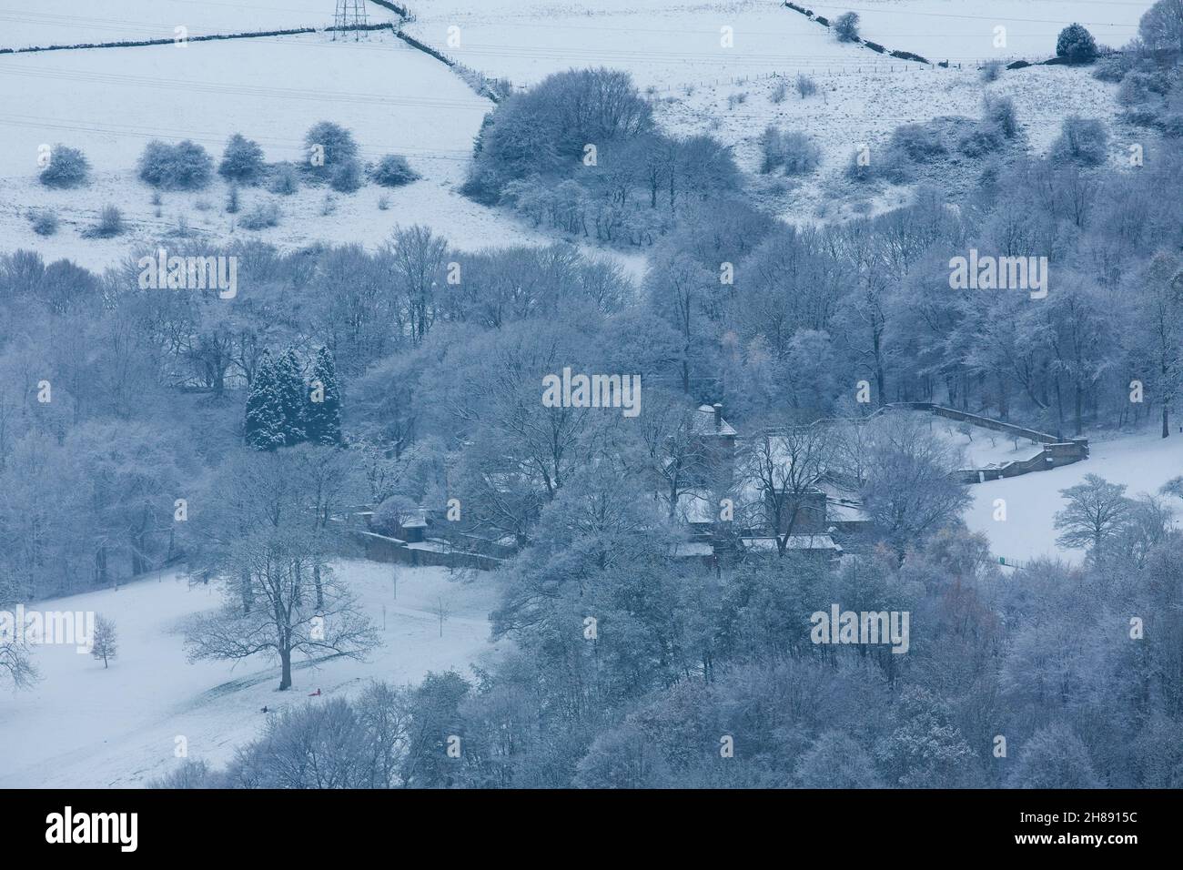 Hiver neige dans la vallée de Shibden près de Halifax, Calvale, West Yorkshire, Royaume-Uni comme les couchers de soleil sur les collines.Une salle Shibden éloignée l'ancienne demeure d'Anne Lister entourée de neige. Banque D'Images