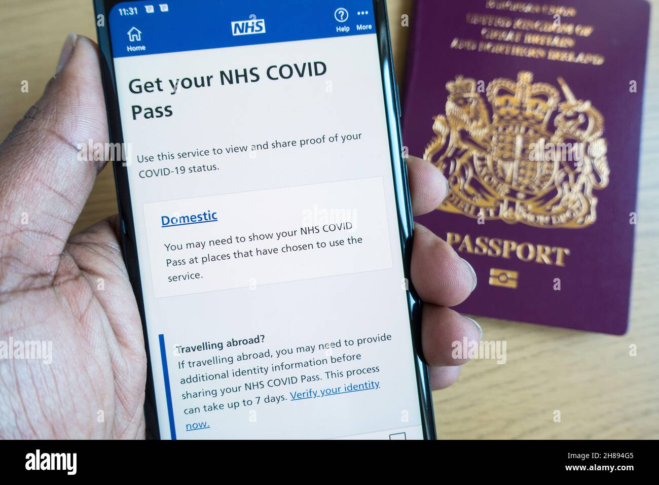 NHS Covid Pass pour les voyages nationaux et internationaux sur un smartphone avec passeport britannique en arrière-plan Banque D'Images