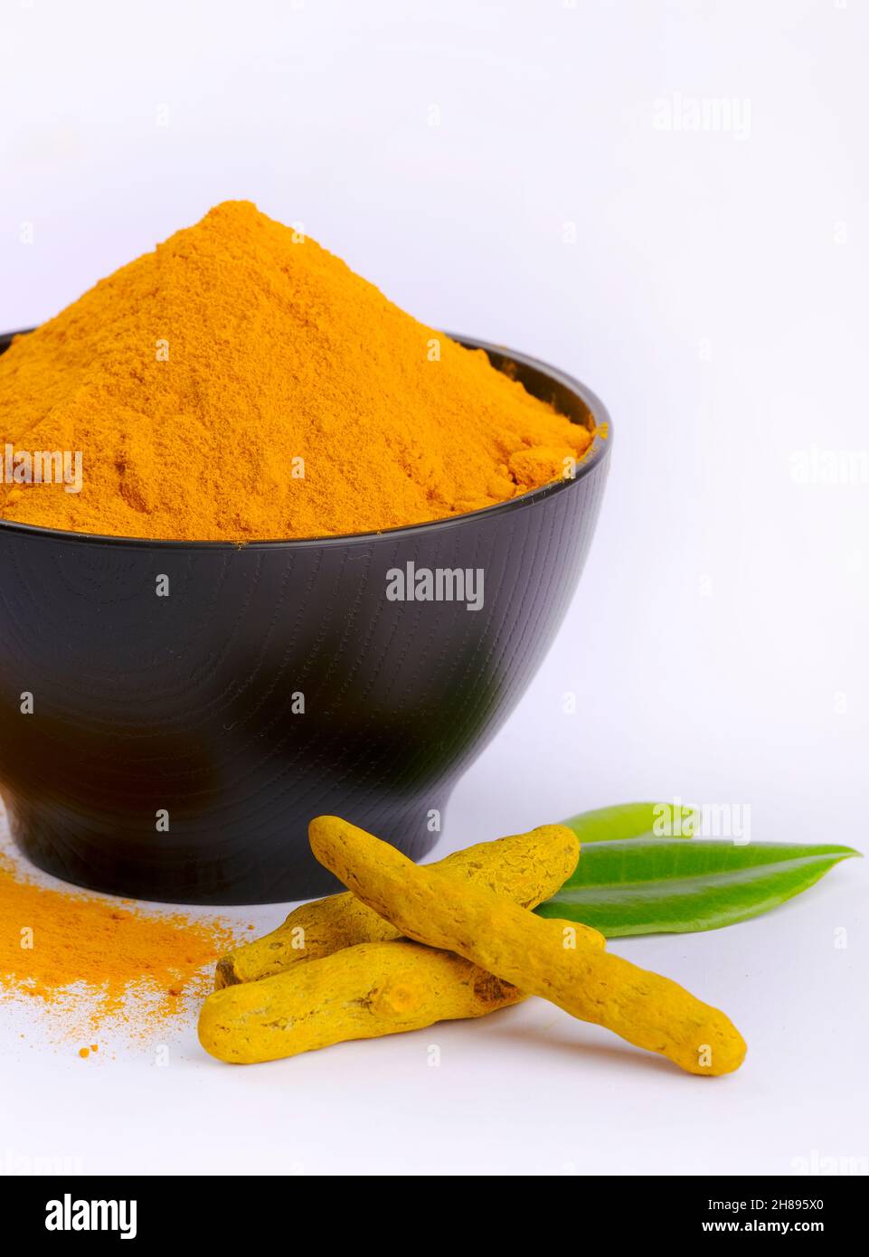 Poudre de curcumine, poudre de curcumine dans un bol à côté des racines de curcuma et poudre de curcuma dispersée sur une surface, isolée sur fond blanc. Banque D'Images