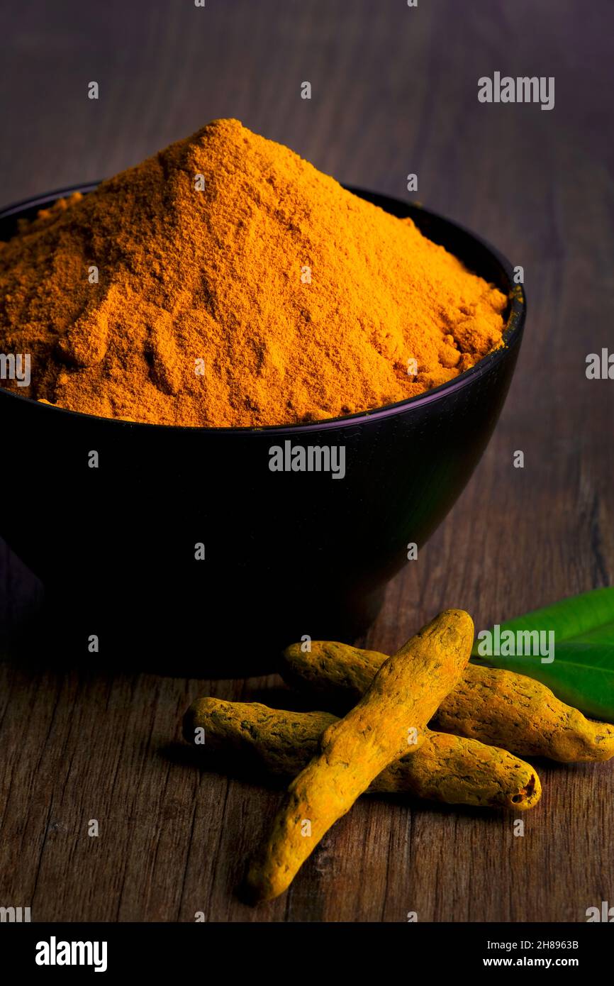Poudre de curcumine, poudre de curcumine dans un bol à côté des racines de curcuma et poudre de curcuma dispersée sur une surface, isolée sur fond blanc. Banque D'Images