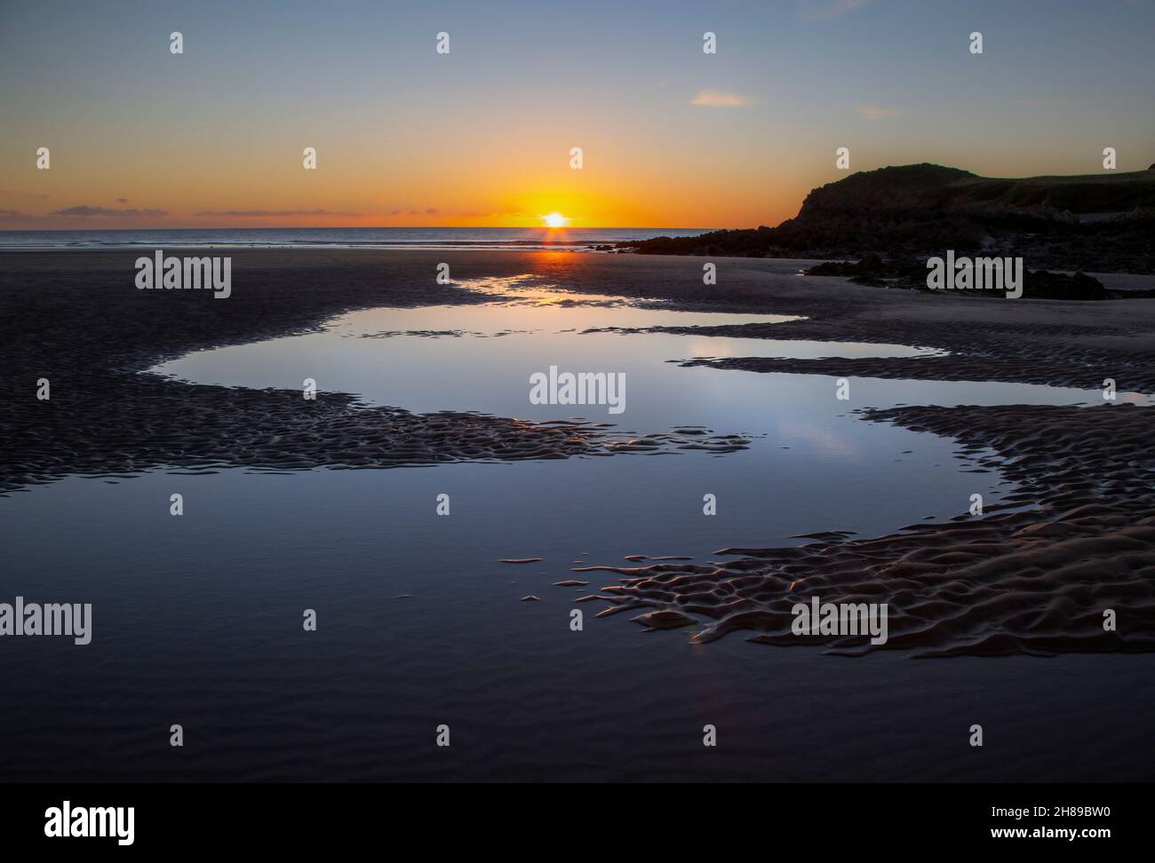 Coucher de soleil sur un ciel d'hiver clair à l'extrémité de la baie de Rhossili sur la péninsule de Gower à Swansea au Royaume-Uni Banque D'Images