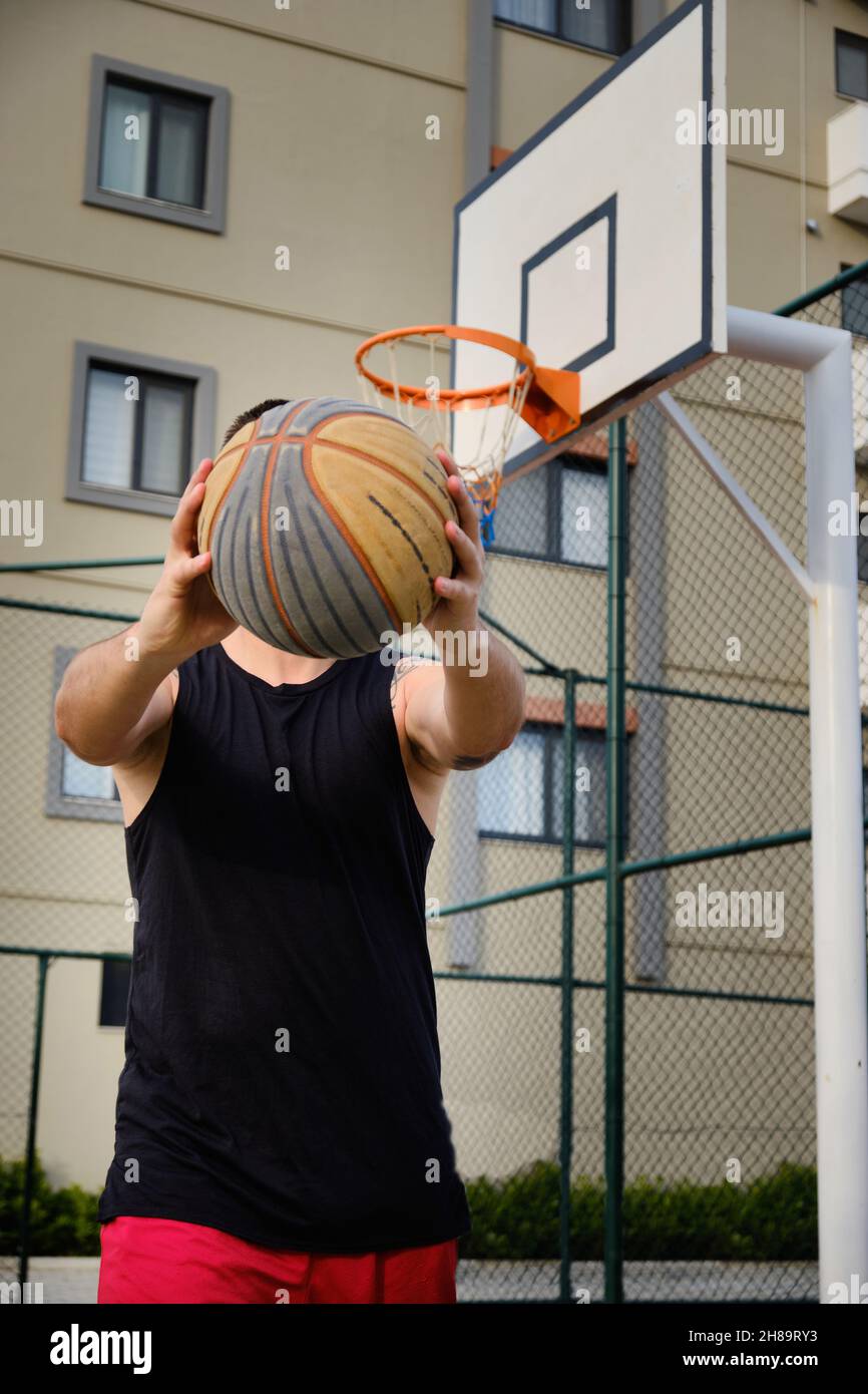 L'homme joue au basket-ball sur le terrain extérieur Banque D'Images