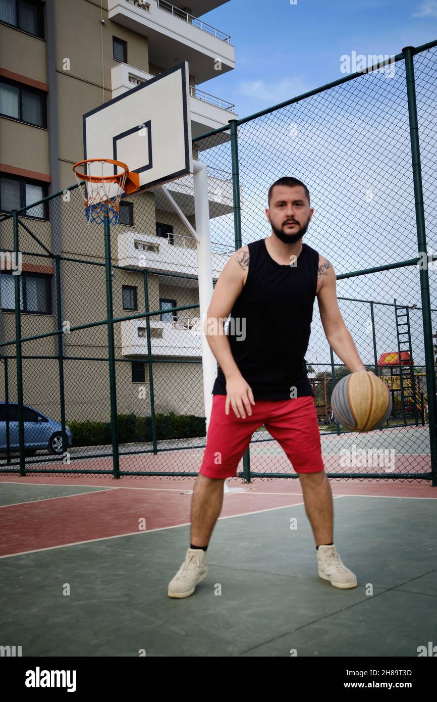 L'homme joue au basket-ball sur le terrain extérieur Banque D'Images