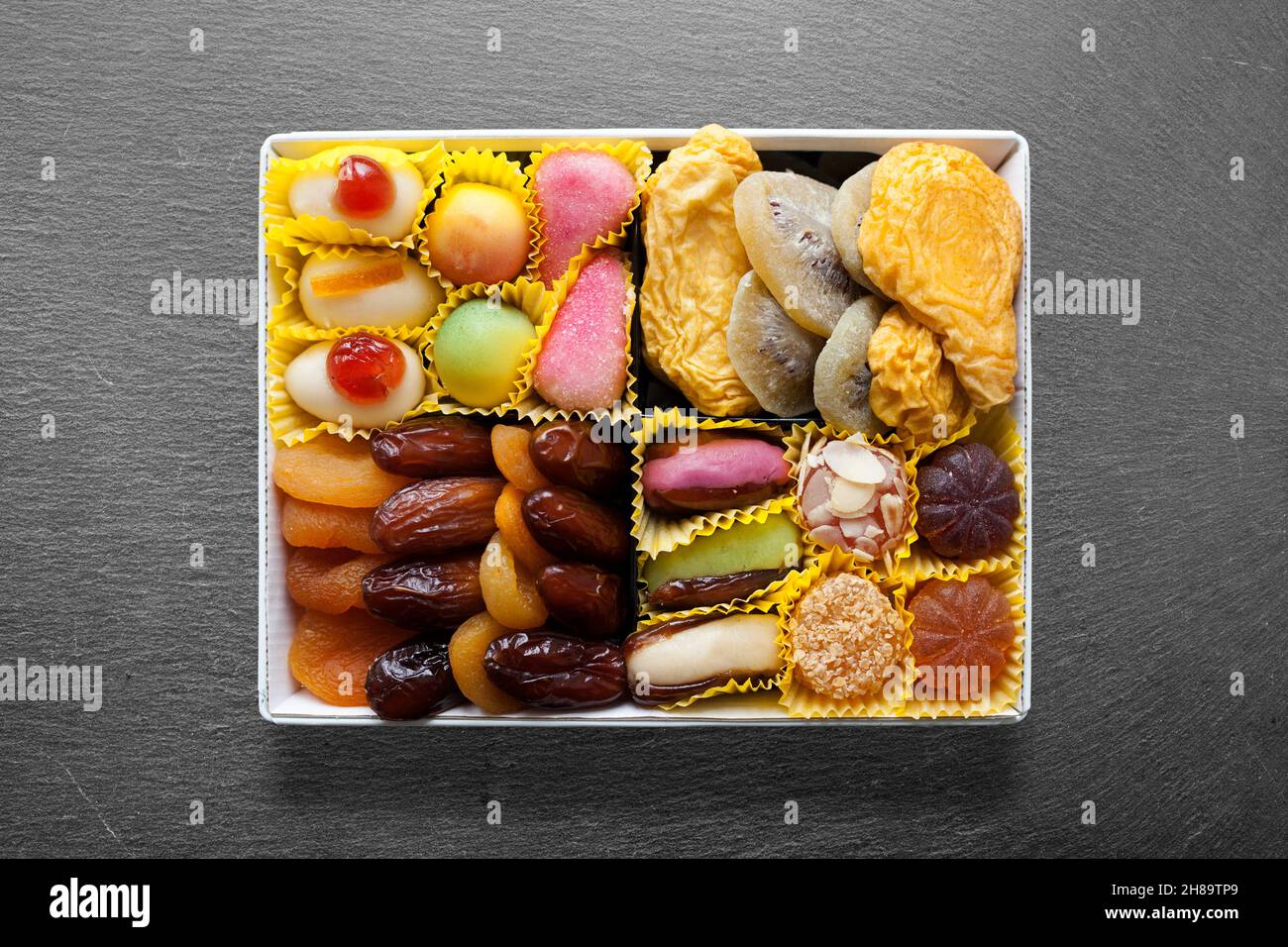 Plateau en ardoise avec au milieu, plat en métal blanc avec bonbons et fruits secs. Banque D'Images