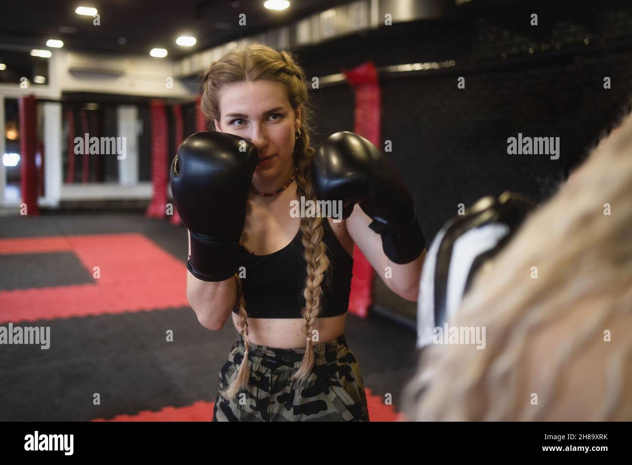 Deux jeunes femmes en gants de boxe font de la sparring, vue du côté de l'un des athlètes.Entraînement de boxe pour femmes dans la salle de sport Banque D'Images