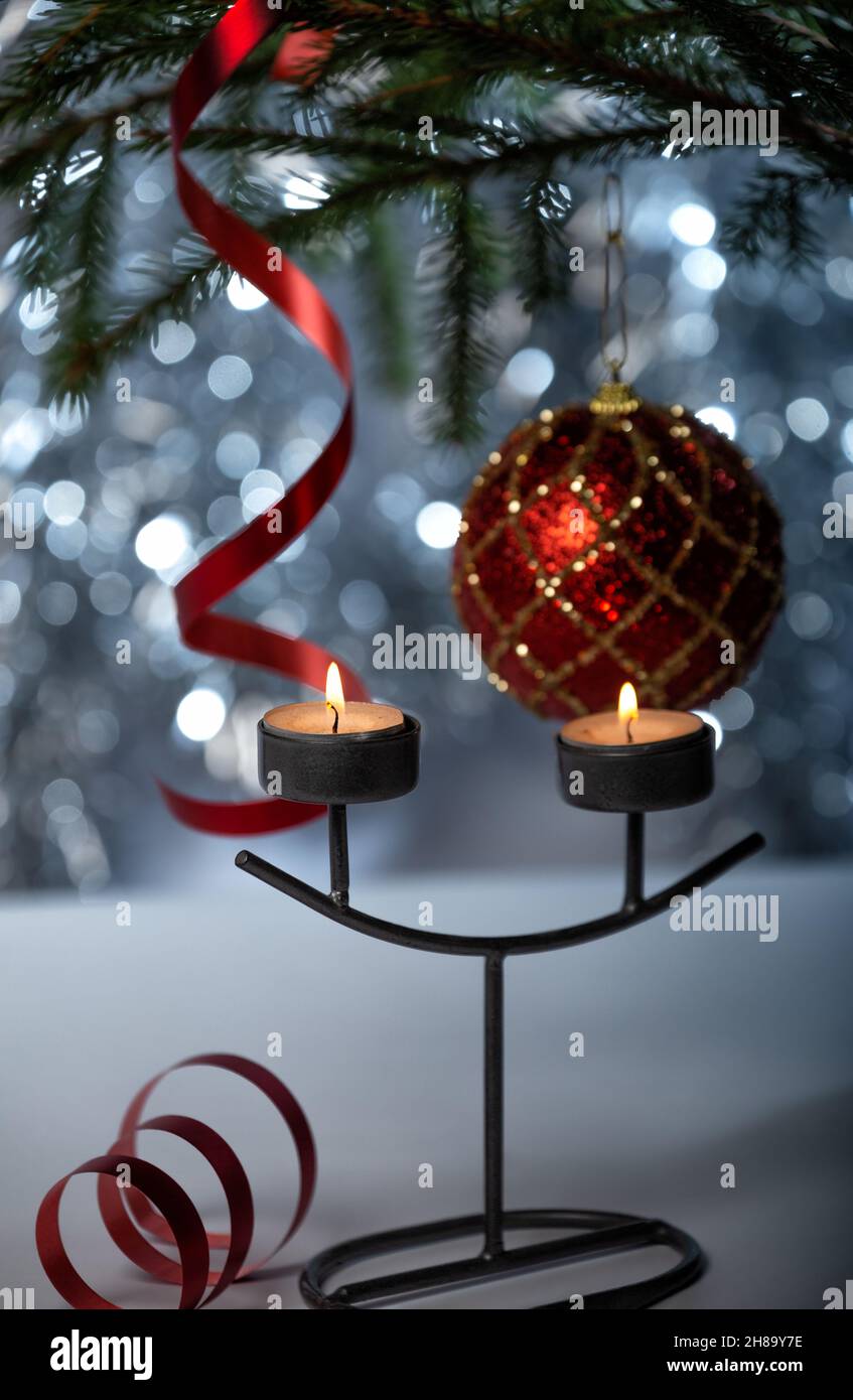 Décorations de Noël.Deux bougies allumées dans un chandelier, une boule rouge et un ruban de banderole sur l'arbre de Noël.Mise au point sélective Banque D'Images
