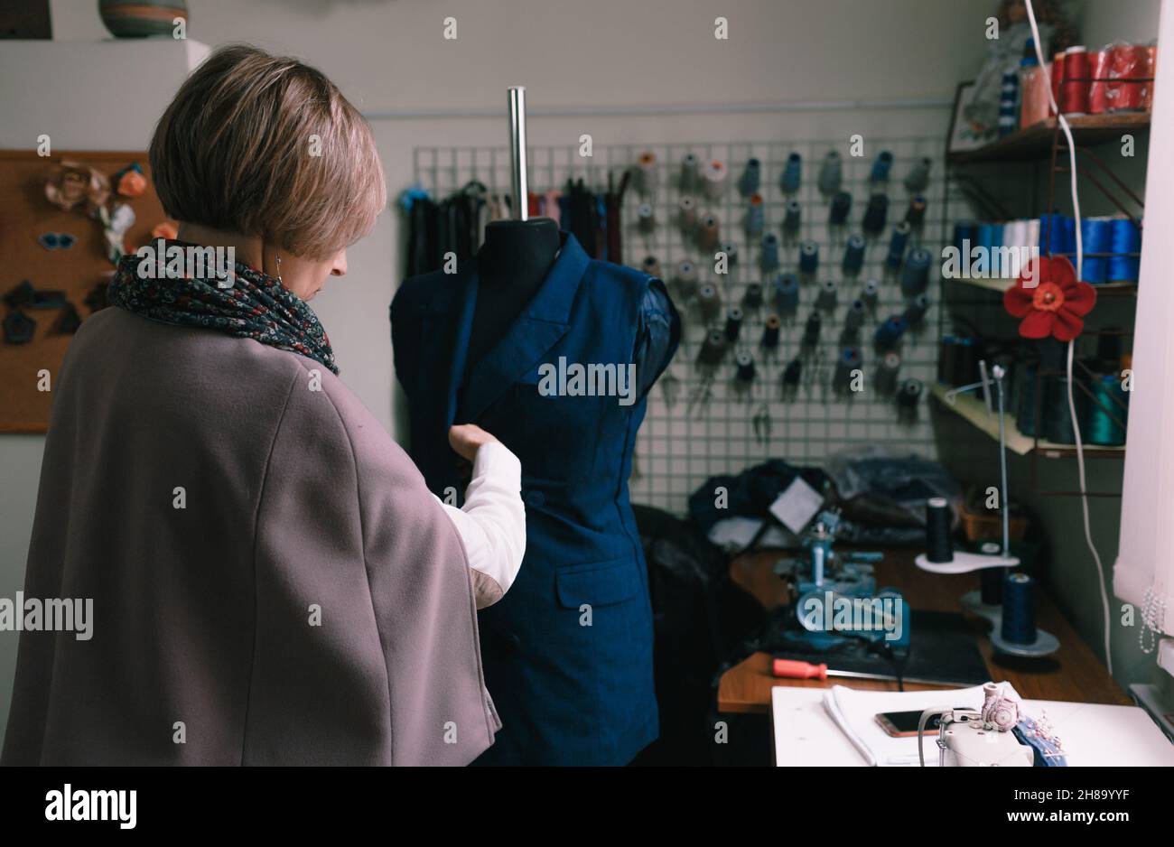 Une couturière féminine superpose manuellement un costume sur un mannequin dans un atelier de couture. Banque D'Images