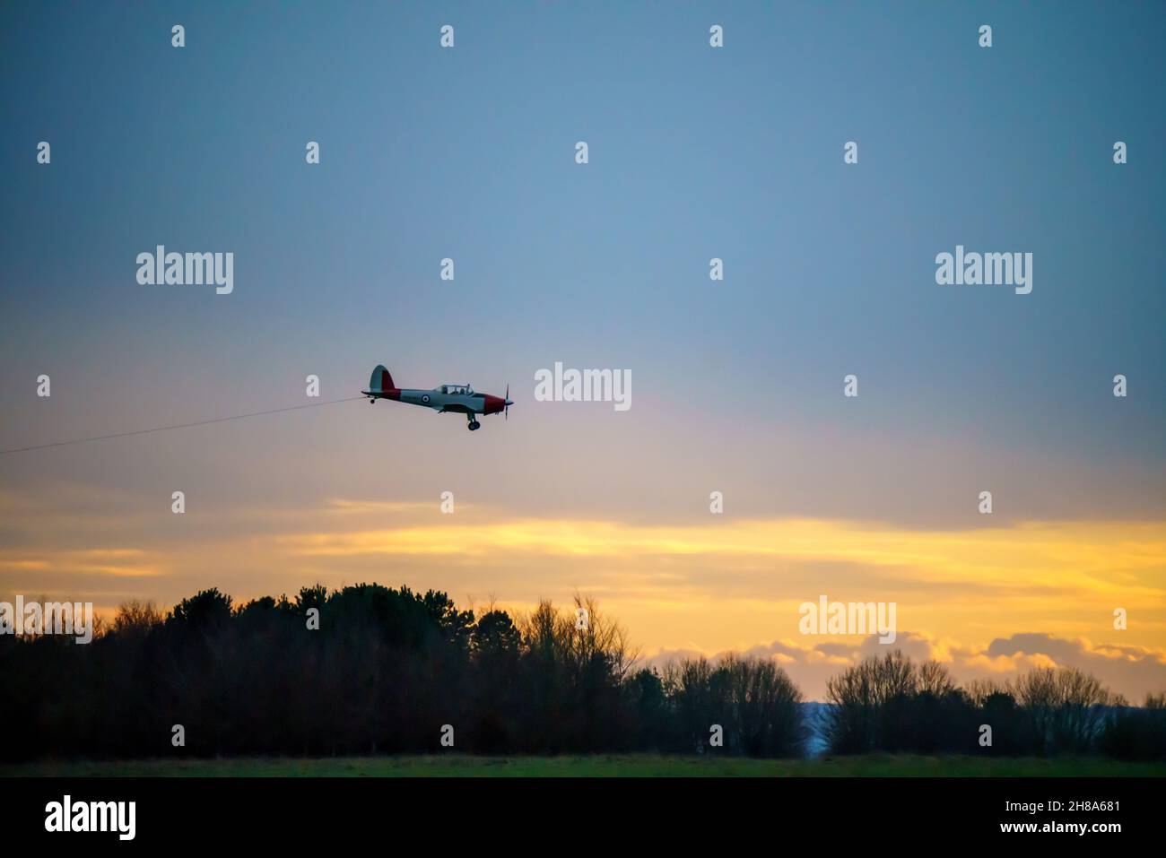 Un DHC-1 Chipmunk de Havilland des années 1950 s'approche de l'atterrissage avec un fond de coucher de soleil, sur une piste d'herbe à l'aérodrome de Netheravon, dans le Wiltshire au Royaume-Uni Banque D'Images