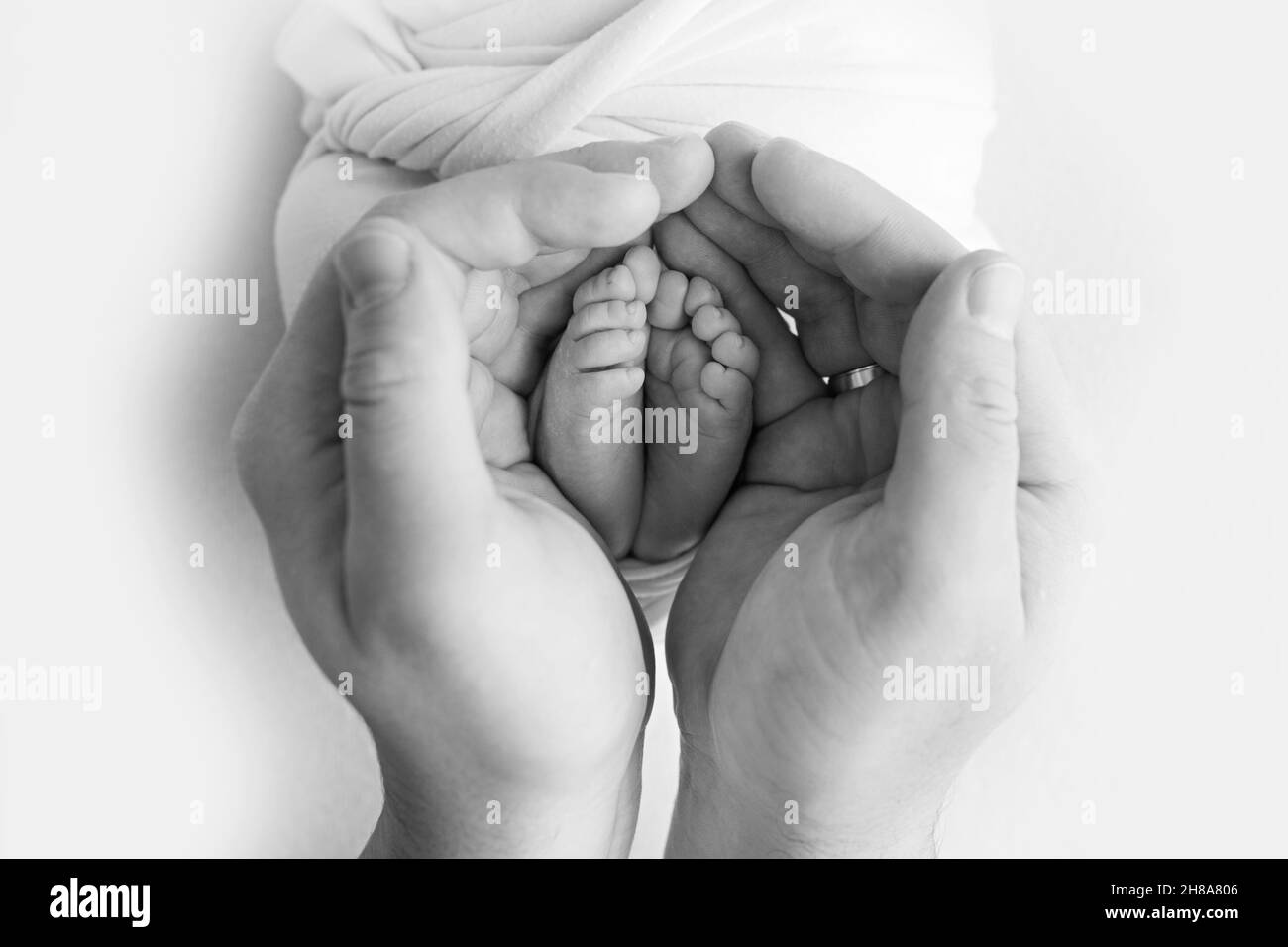 Jambes, orteils, pieds et talons d'un nouveau-né.Avec les mains des parents. Banque D'Images