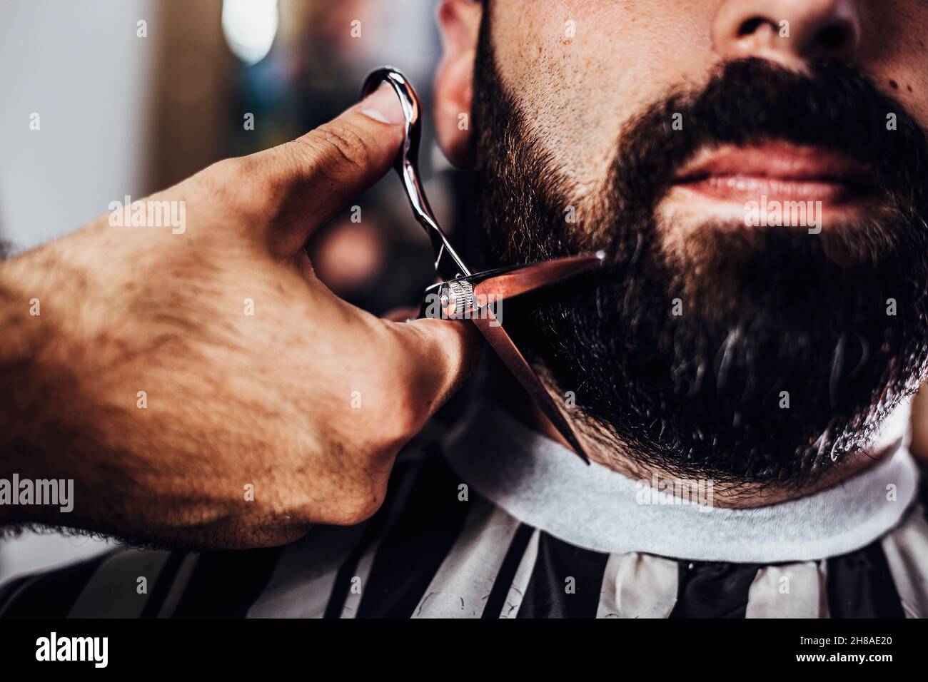 Barbier coupant la barbe d'un client avec un ciseau.Barbe coupée au salon de coiffure. Banque D'Images
