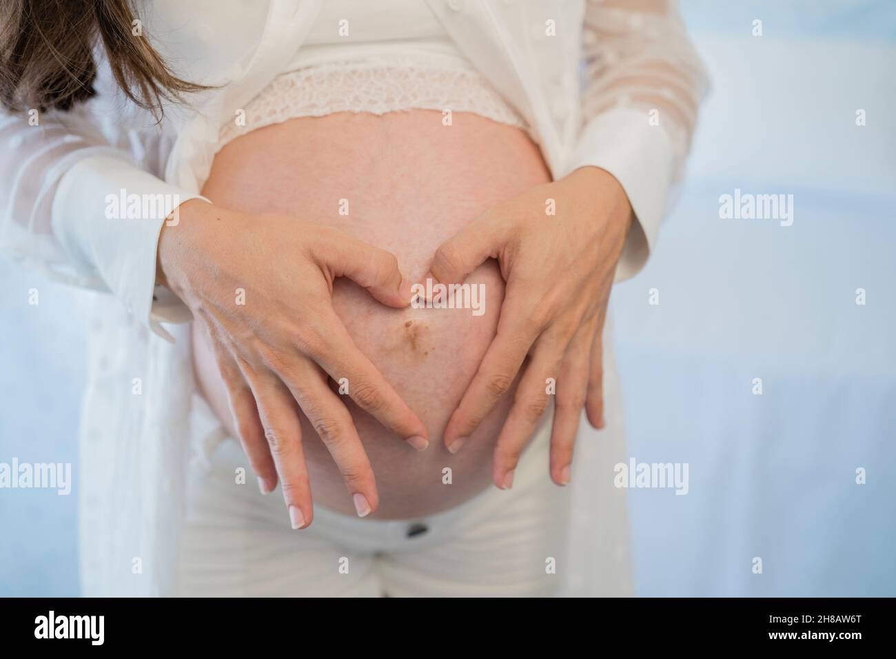 Crop femme enceinte touchant le ventre doucement dans la pièce Banque D'Images