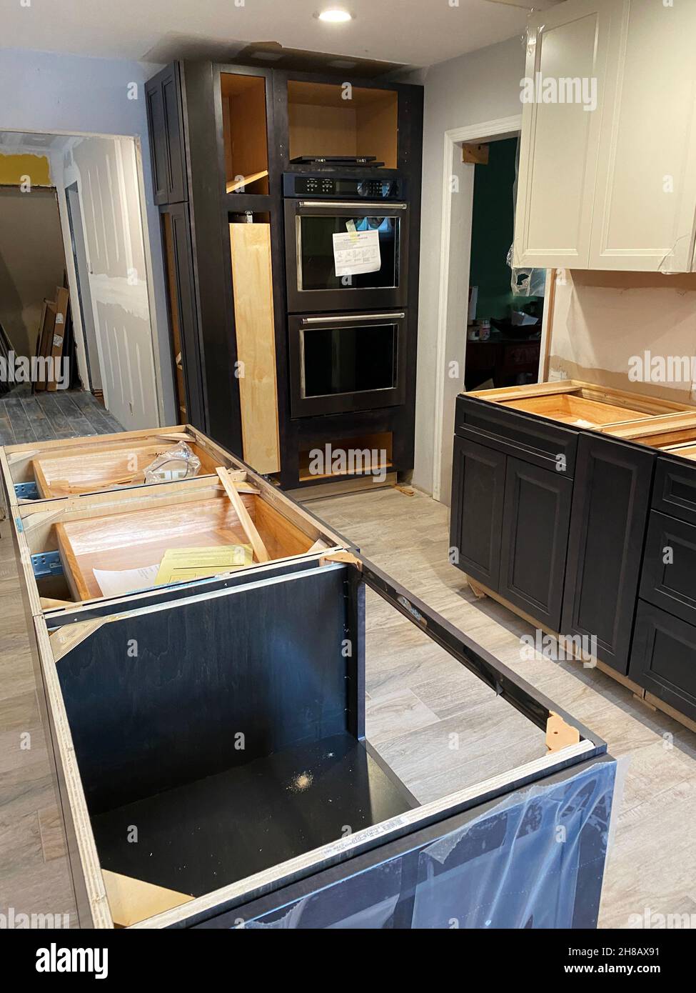 Une rénovation résidentielle de la cuisine en construction avec de nouveaux fours et comptoirs et sol carrelé. Banque D'Images