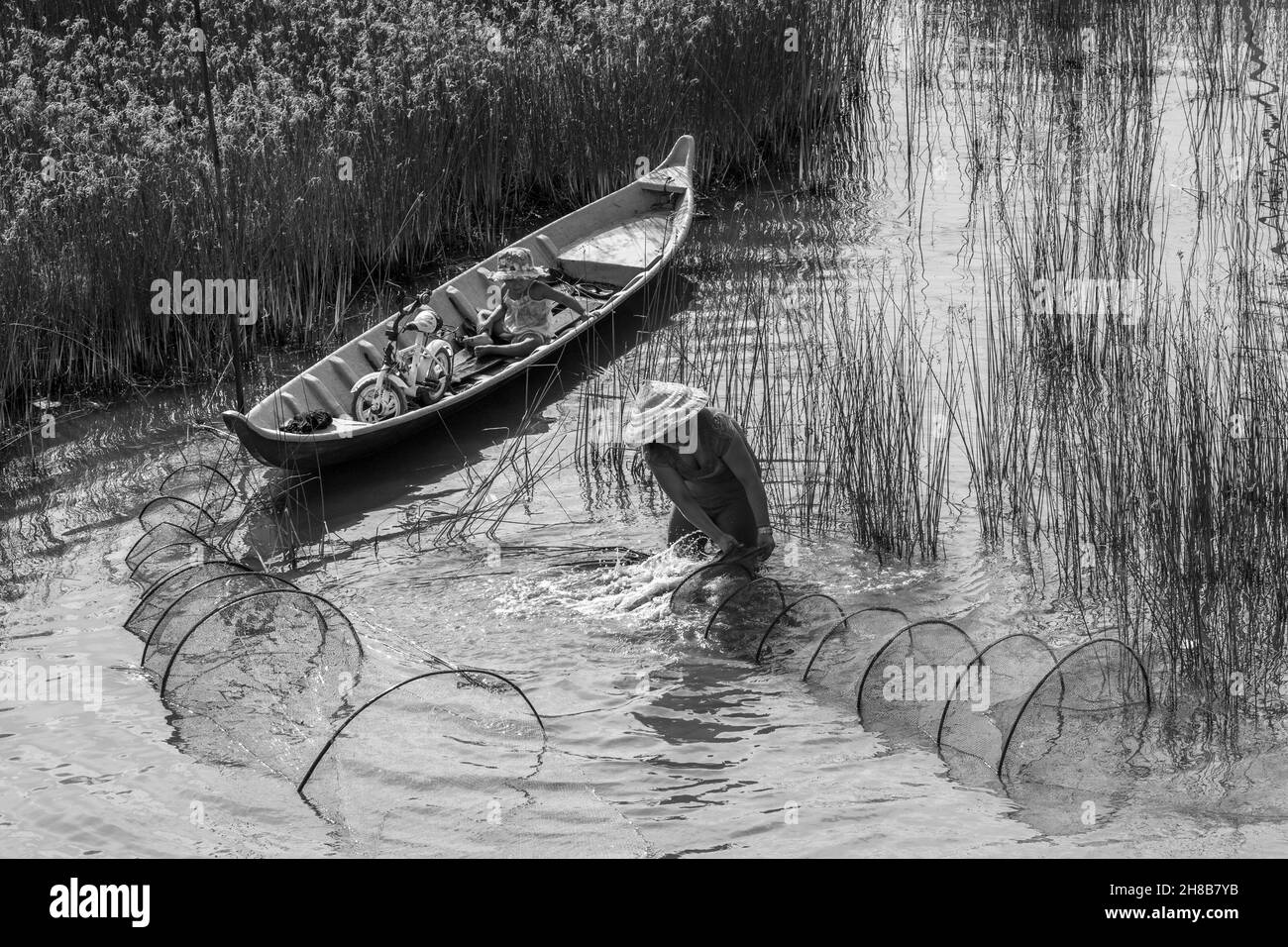 143 / 5000 Kết quả dịch travailler sur le terrain la mère a placé avec attention un filet de pêche, et sa fille s'est assise sur le bateau pour jouer.C'est la scène Banque D'Images