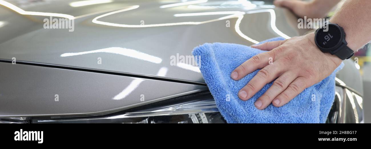 Homme nettoyant une voiture avec un chiffon en microfibre Banque D'Images